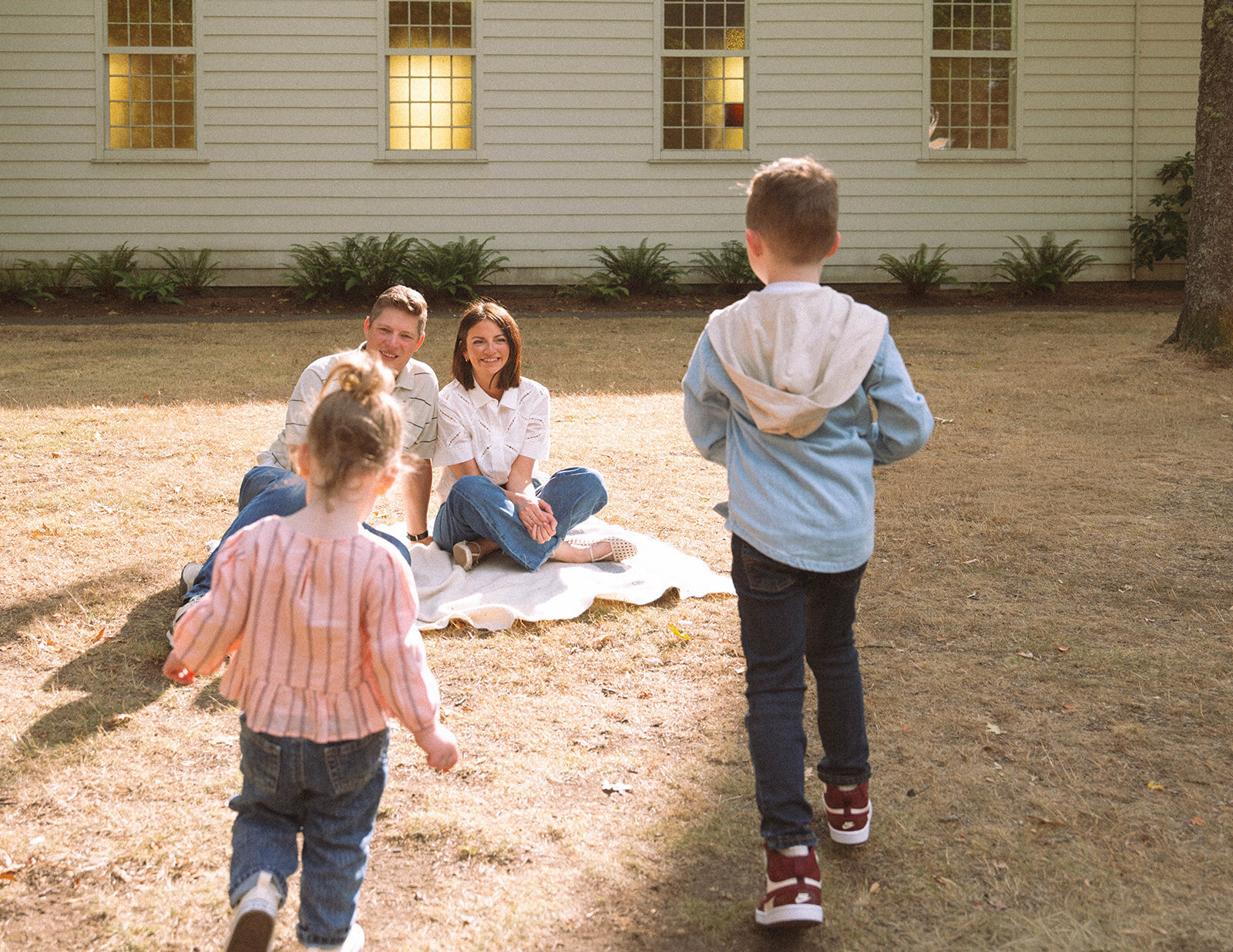 Irvine family photography session outdoors with parents sitting together and kids playing nearby.