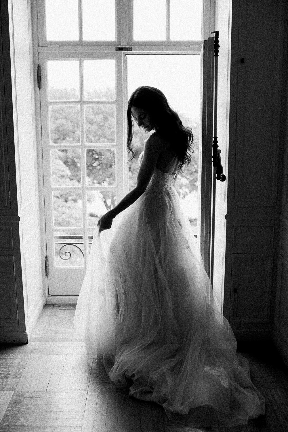 bride in window adjusting dress