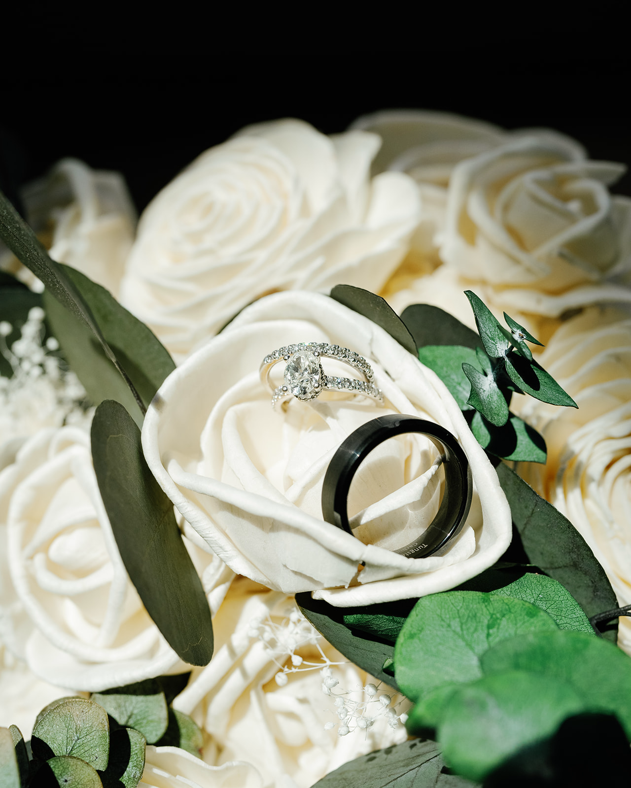Wedding rings sitting a top white rose bridal bouquet | Megan Smith Photography