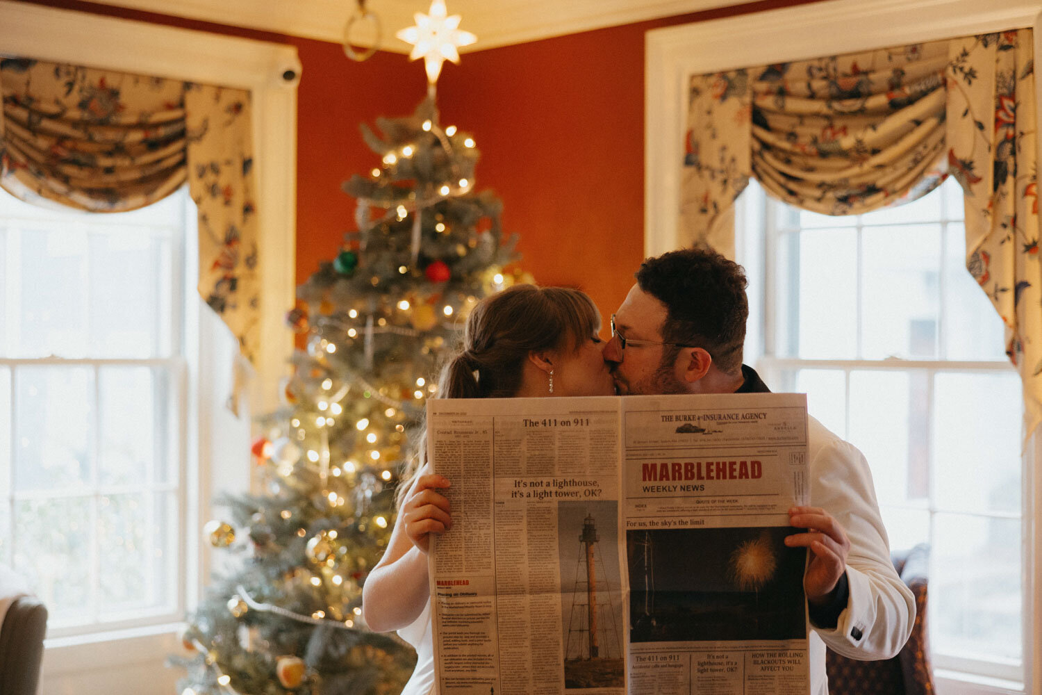 Bride and groom kissing while holding a newspaper