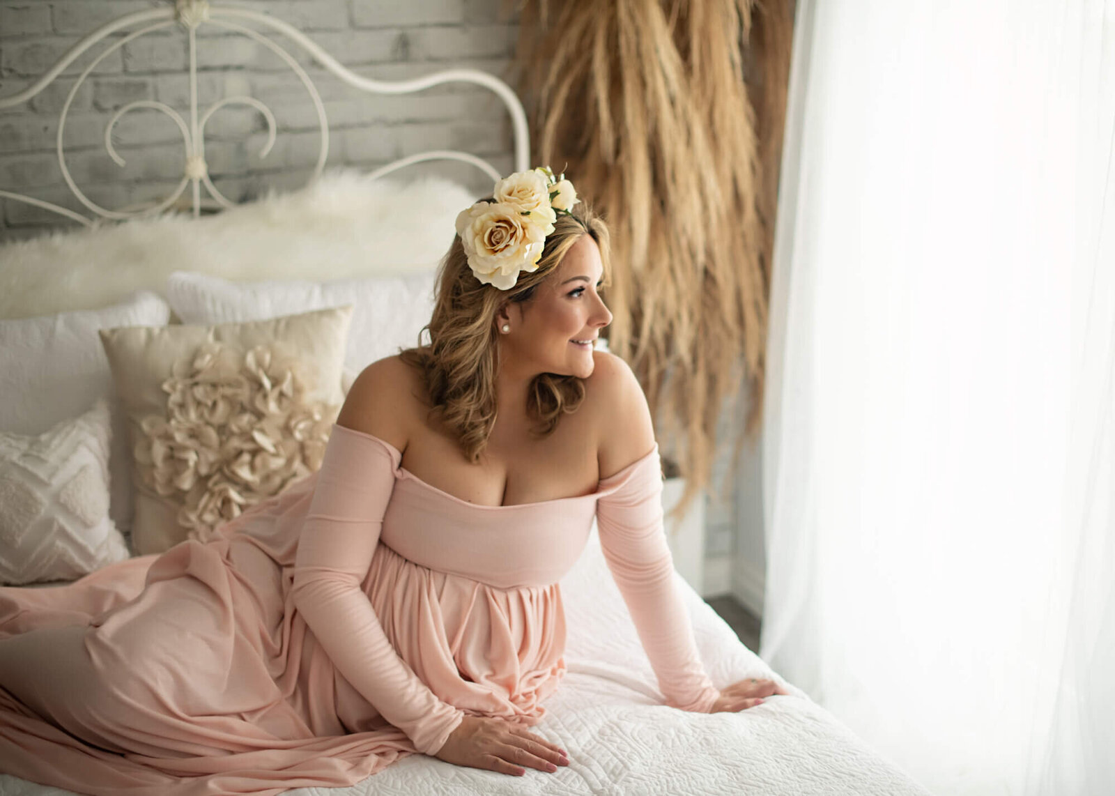 Expectant mother in long sleeved pale pink gown with floral halo