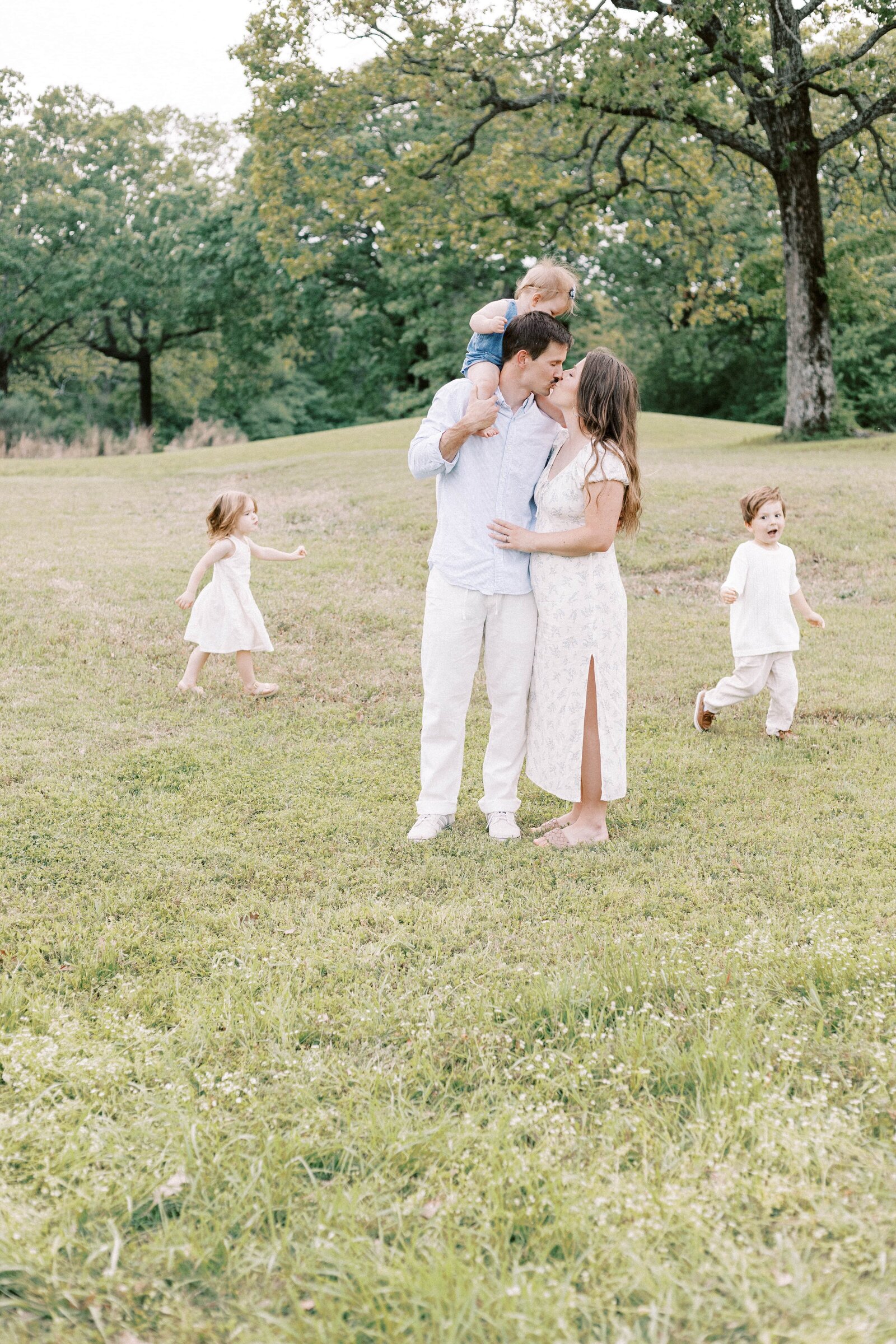 parents hugging while children run around in family photos in peoria illinois 