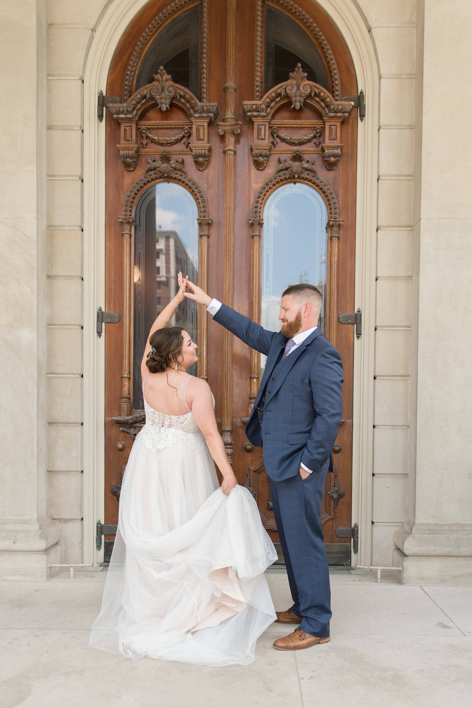 couple standing in front of wooden door twirling at capitol building in Lansing, Michigan