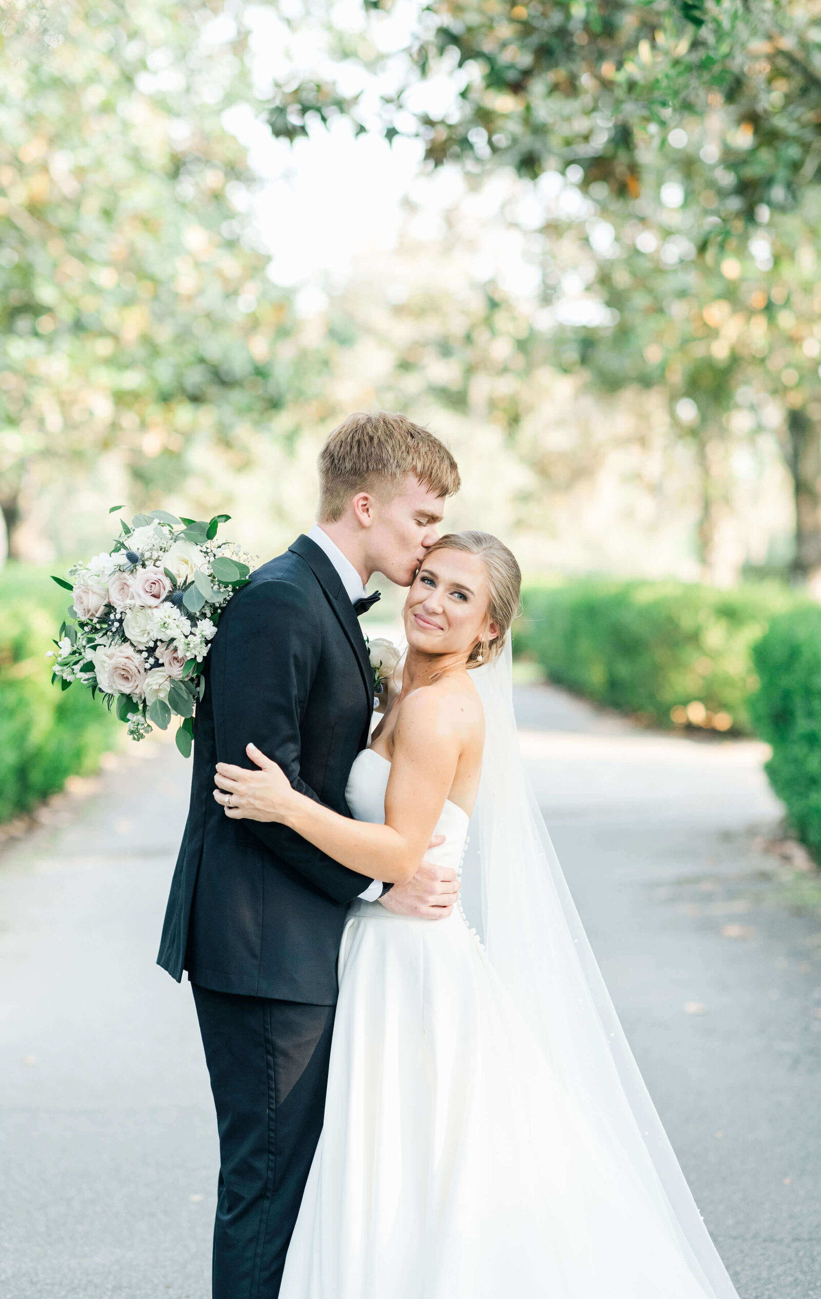 Groom kissing bride in a glowy light and airy background