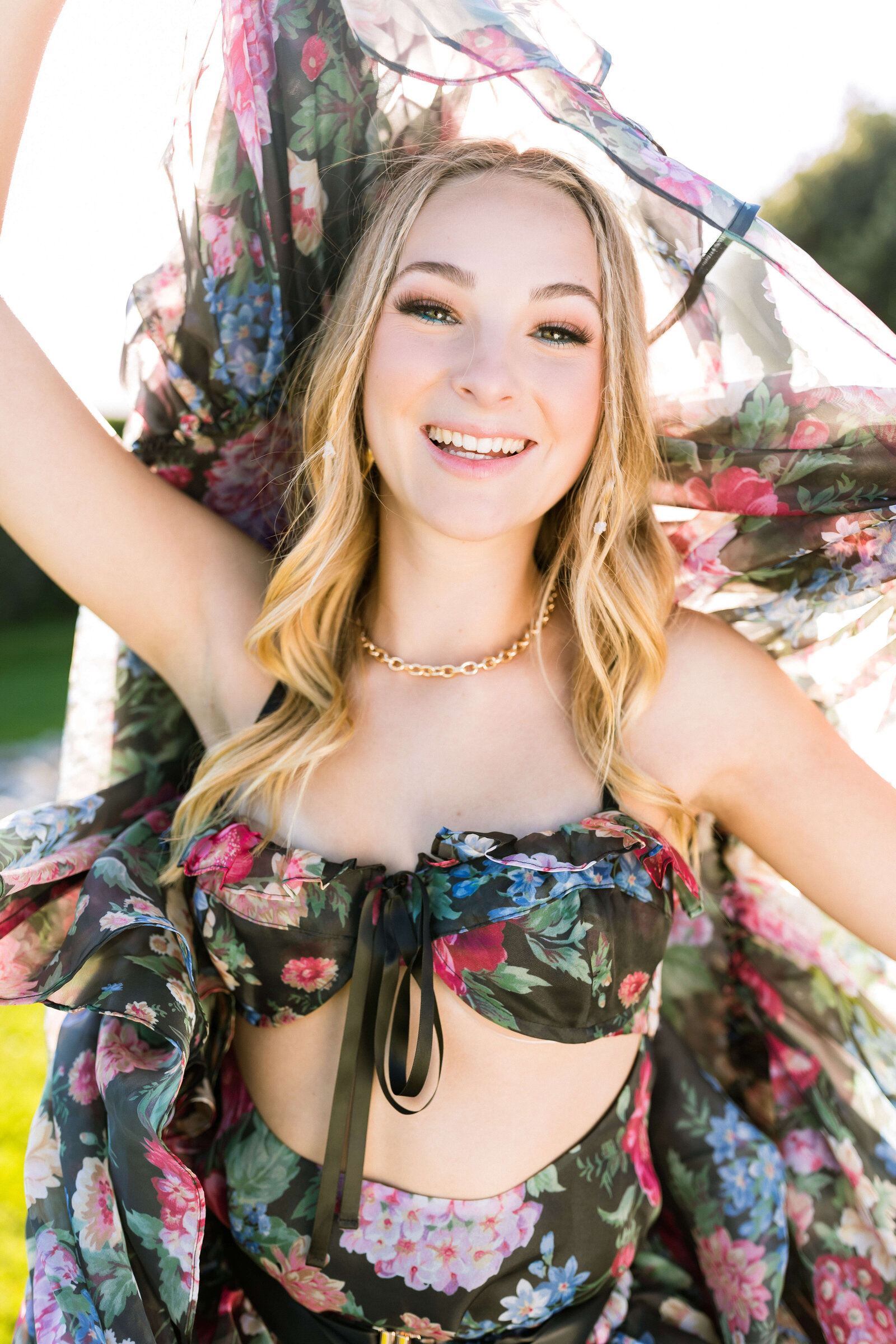 blonde girl wearing black floral dress with gold necklace