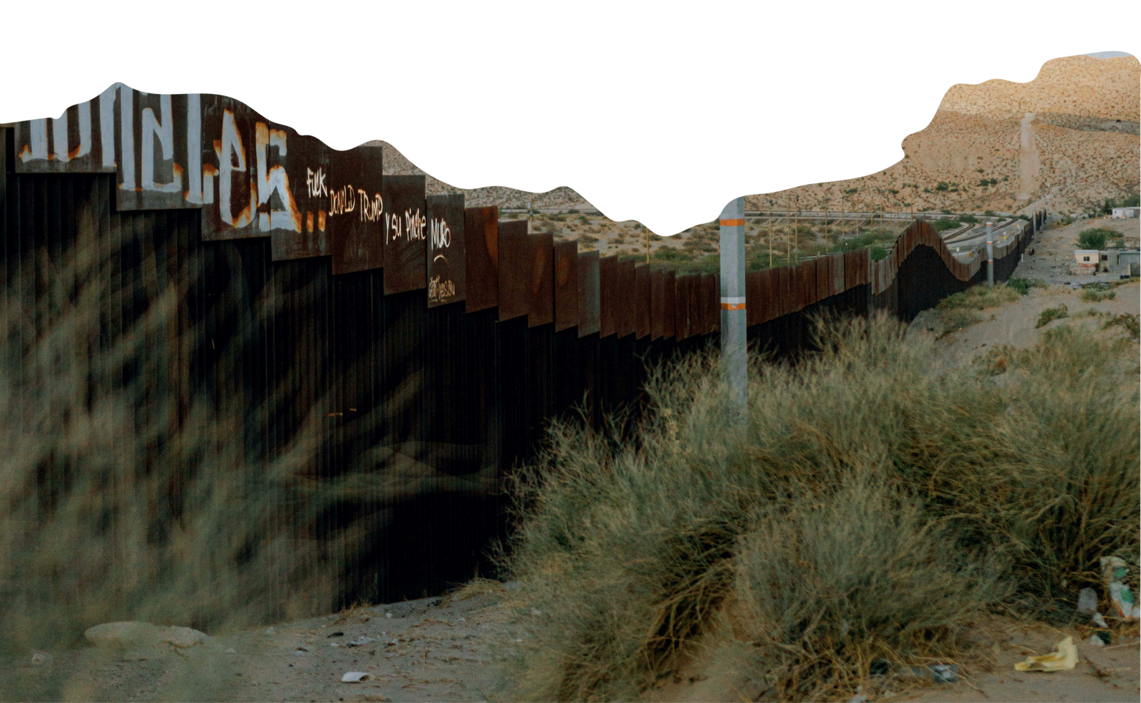 An image of the border wall that divides the deserts of Mexico and the southern United States which is rusty and covered in graffiti