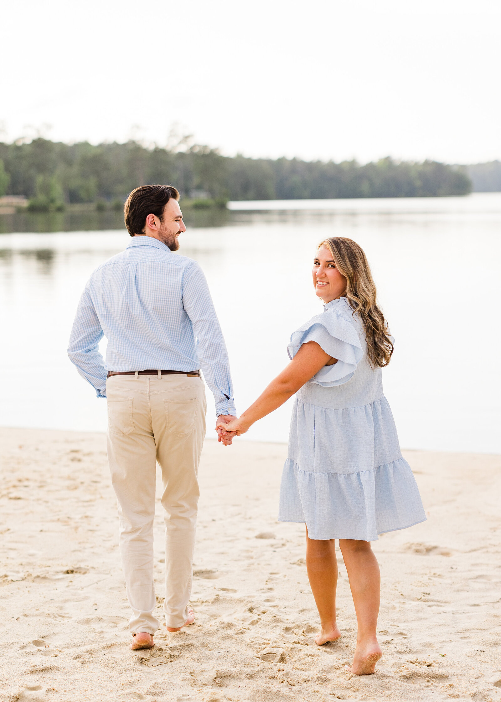 Julianna and Josh laughing together during their engagement session at the beach, photographed by Abby Bell Photography.