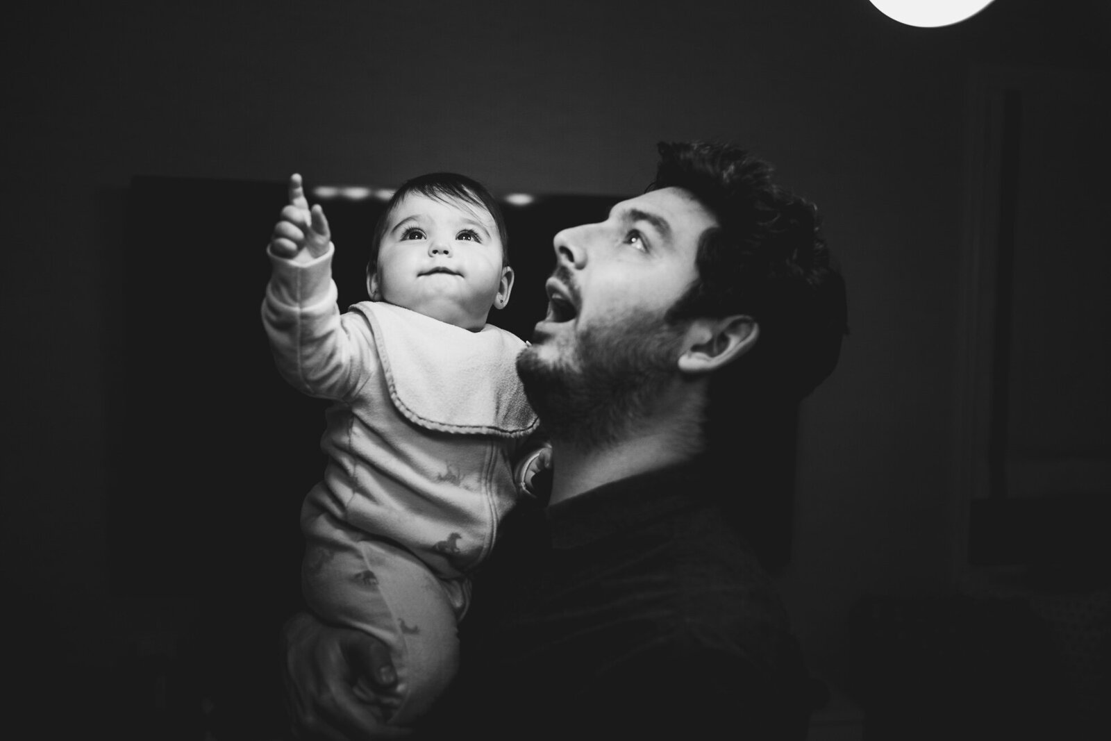 little girl point to a light bulb from dad's arms
