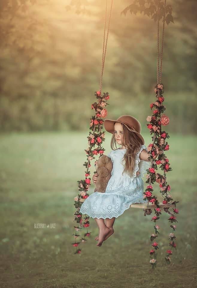 girl on swing for her photo session outdoors with her teddy bear