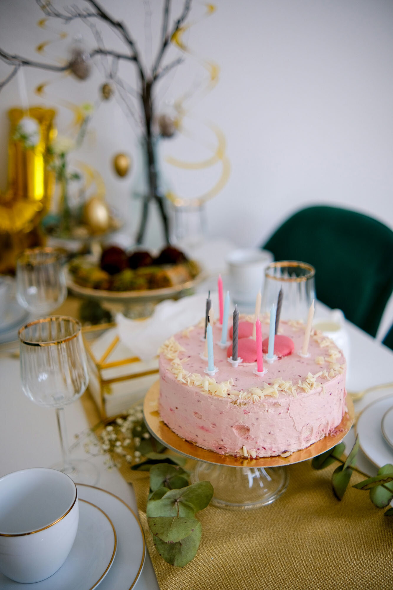 Pink cake with candles on it sits on a table