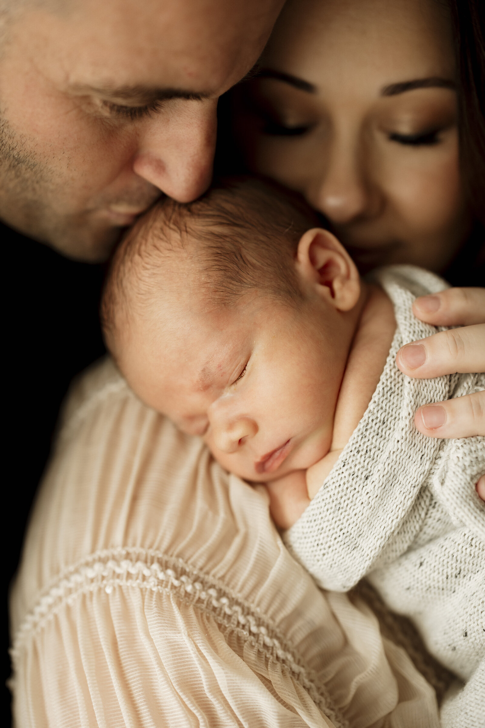 Studio newborn family photography in Perth – a beautiful, intimate portrait of new parents holding their baby in soft natural light.