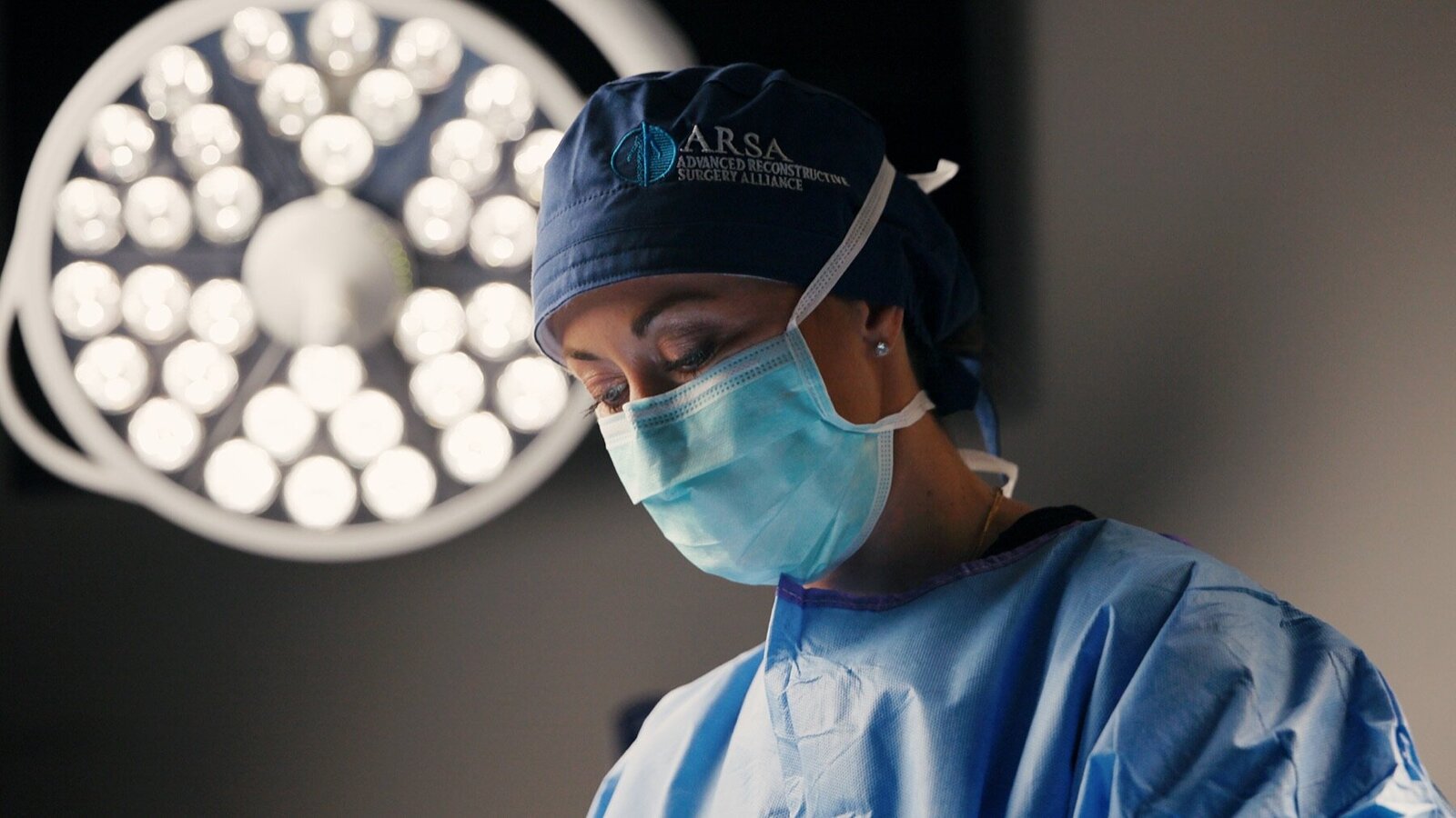 Surgeon in a cap and mask under an operating room light