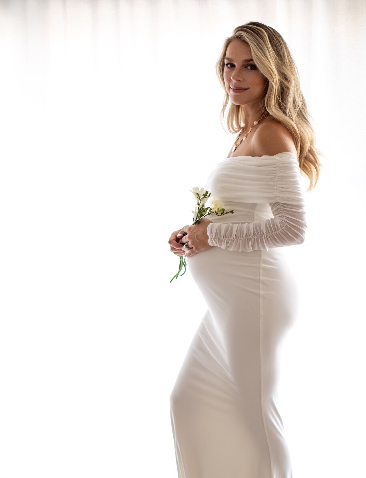 Peaceful maternity photo featuring a woman in a soft, airy white dress cradling her belly, captured by Philadelphia maternity photographers.