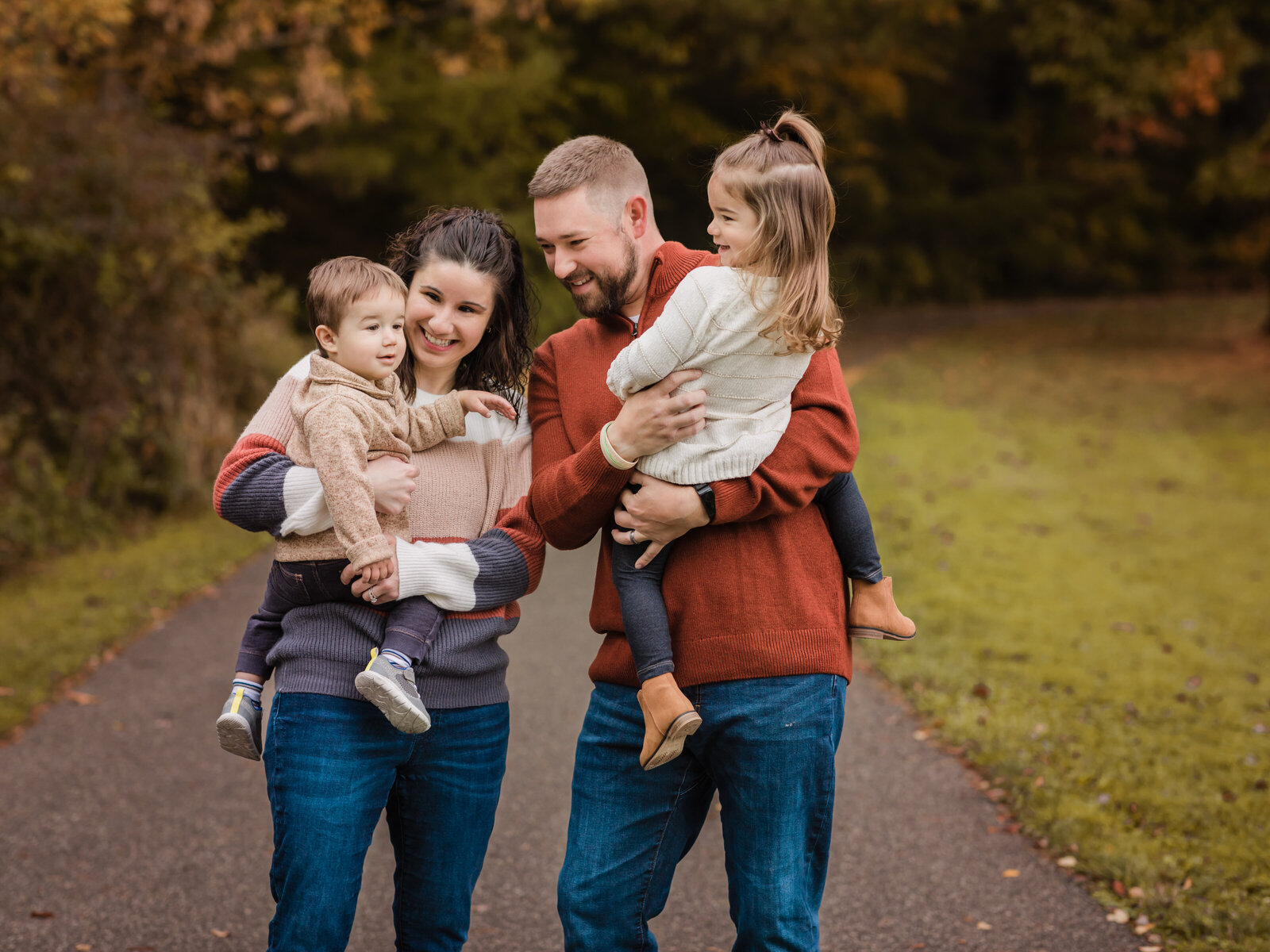 mom and dad holding son and daughter laughing for fall family portraits