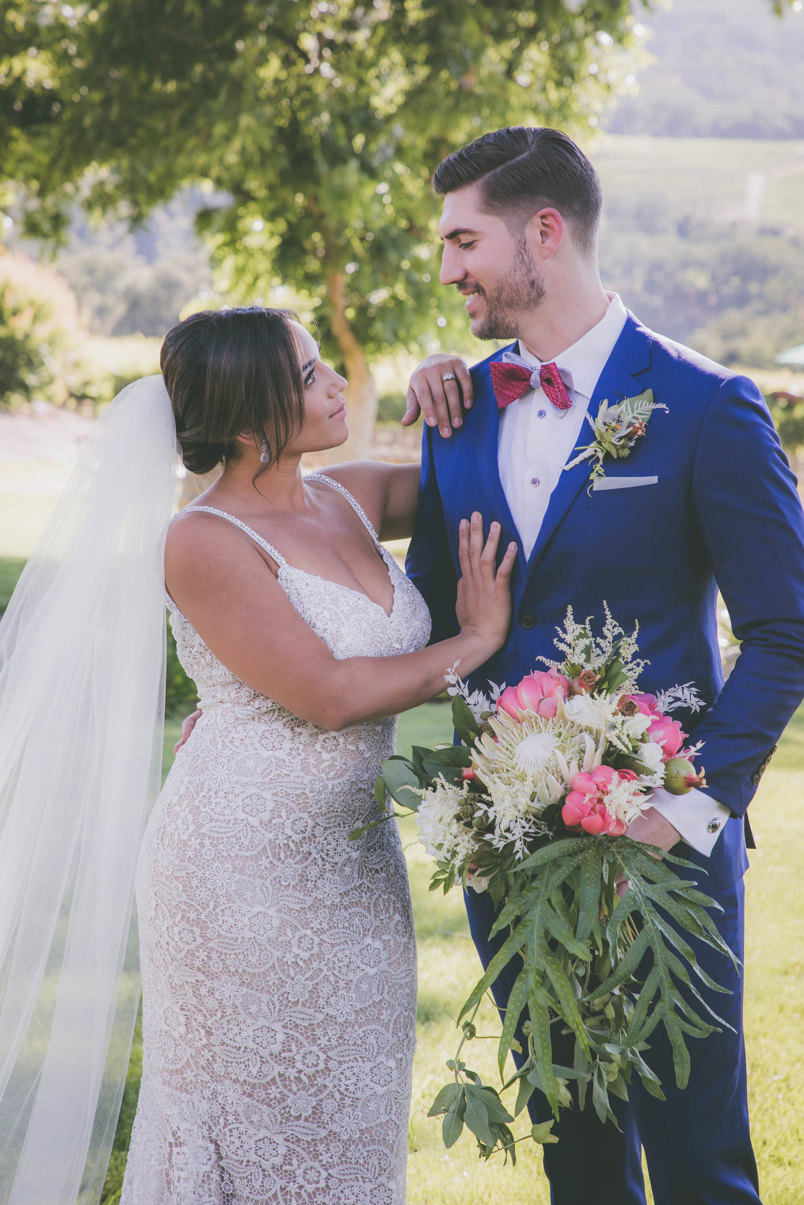 Bride places hands on groom and stares while he holds bouquet in Carmel.