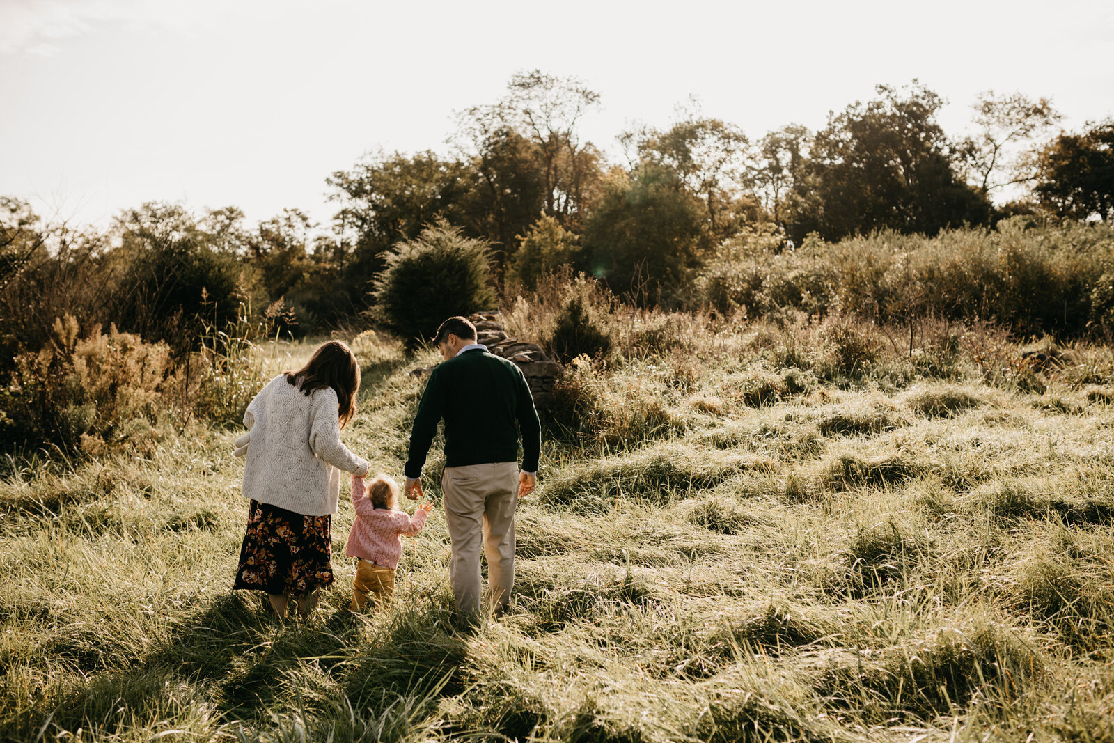 A family walks through a field at sunrise