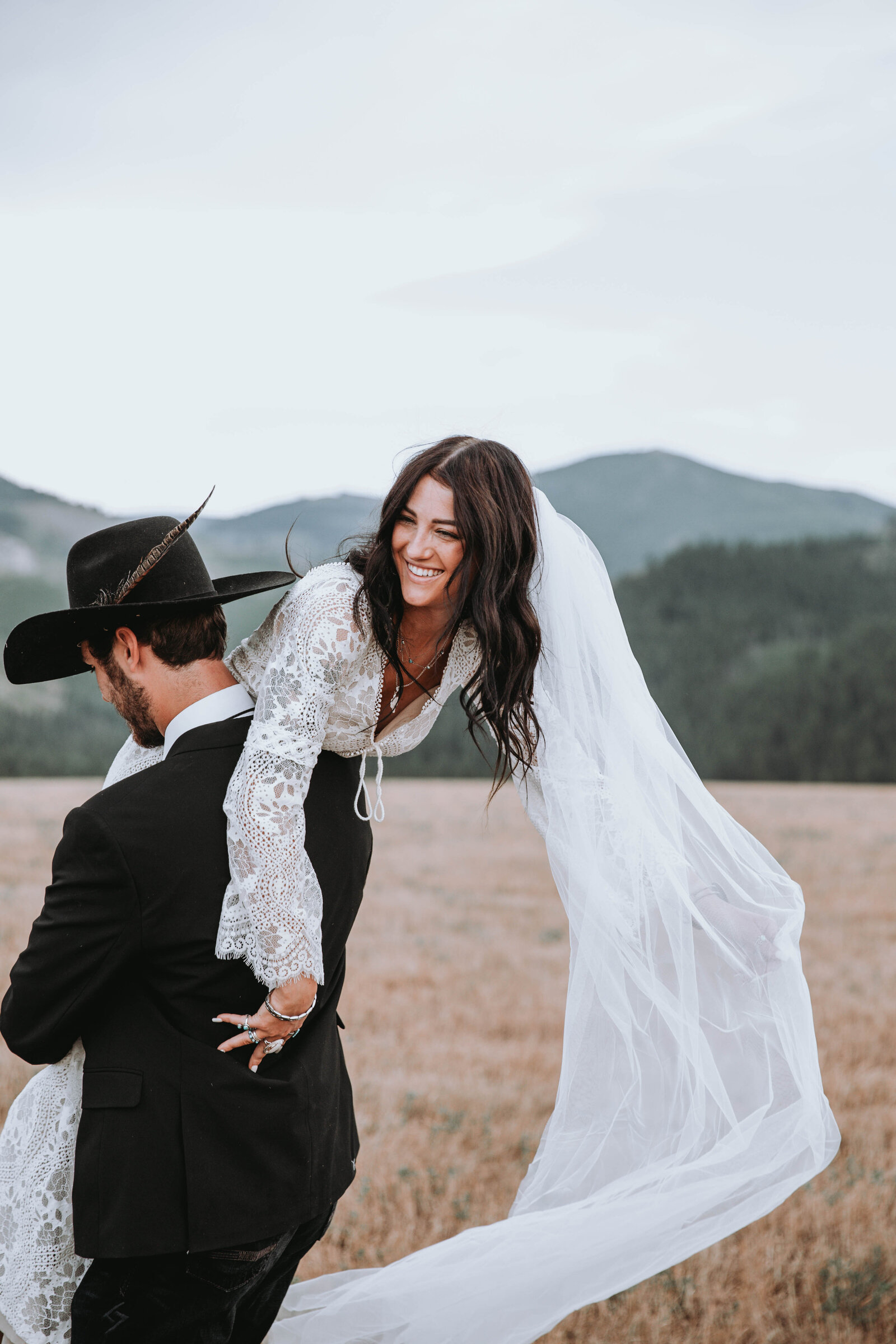 blushing bride gets lifted and twirled by her groom while her veil flows in the wind captured by Idaho Falls Wedding Photographer