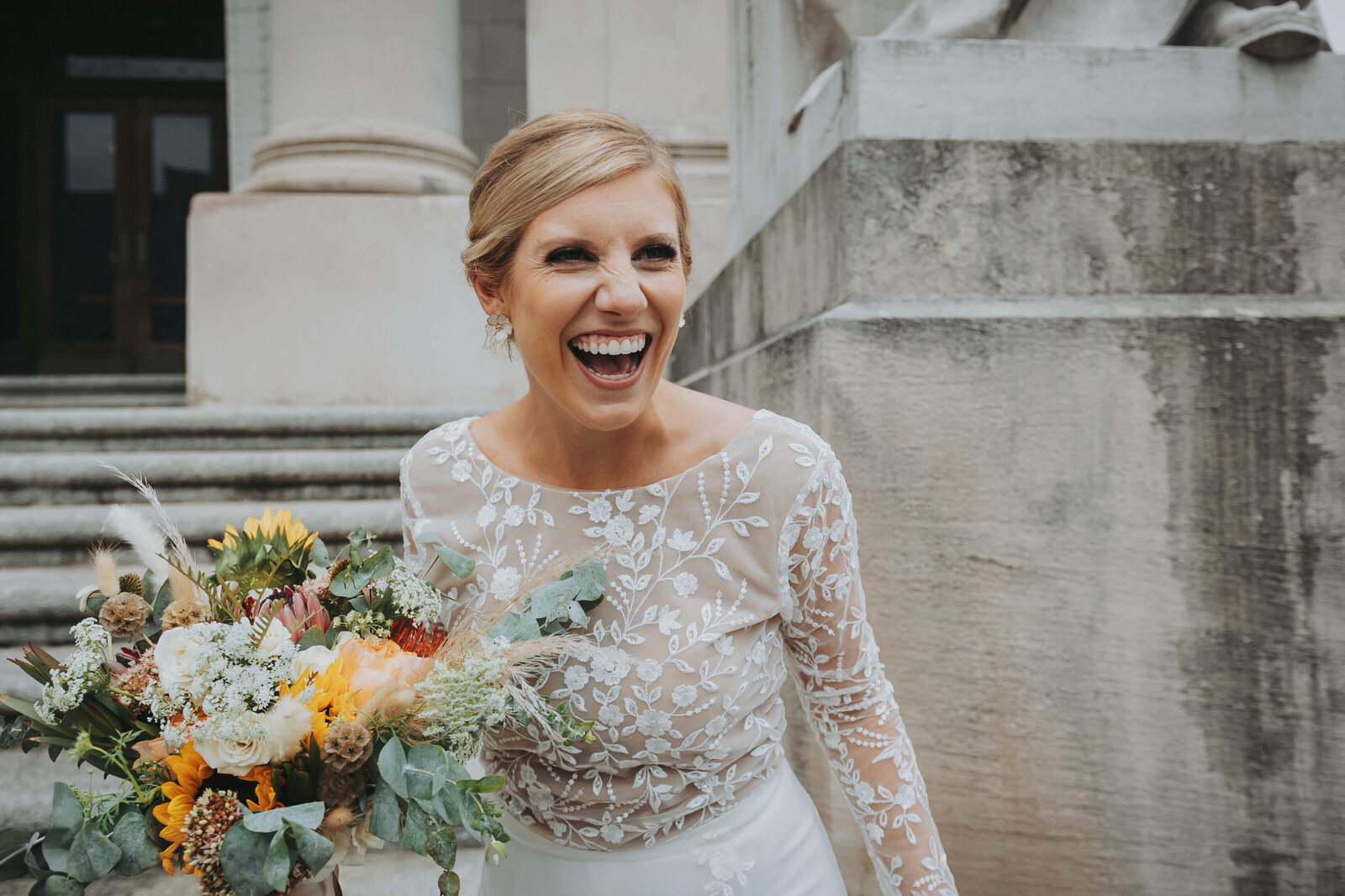 A Bride laughs while holding her bouquet after her intimate courthouse wedding