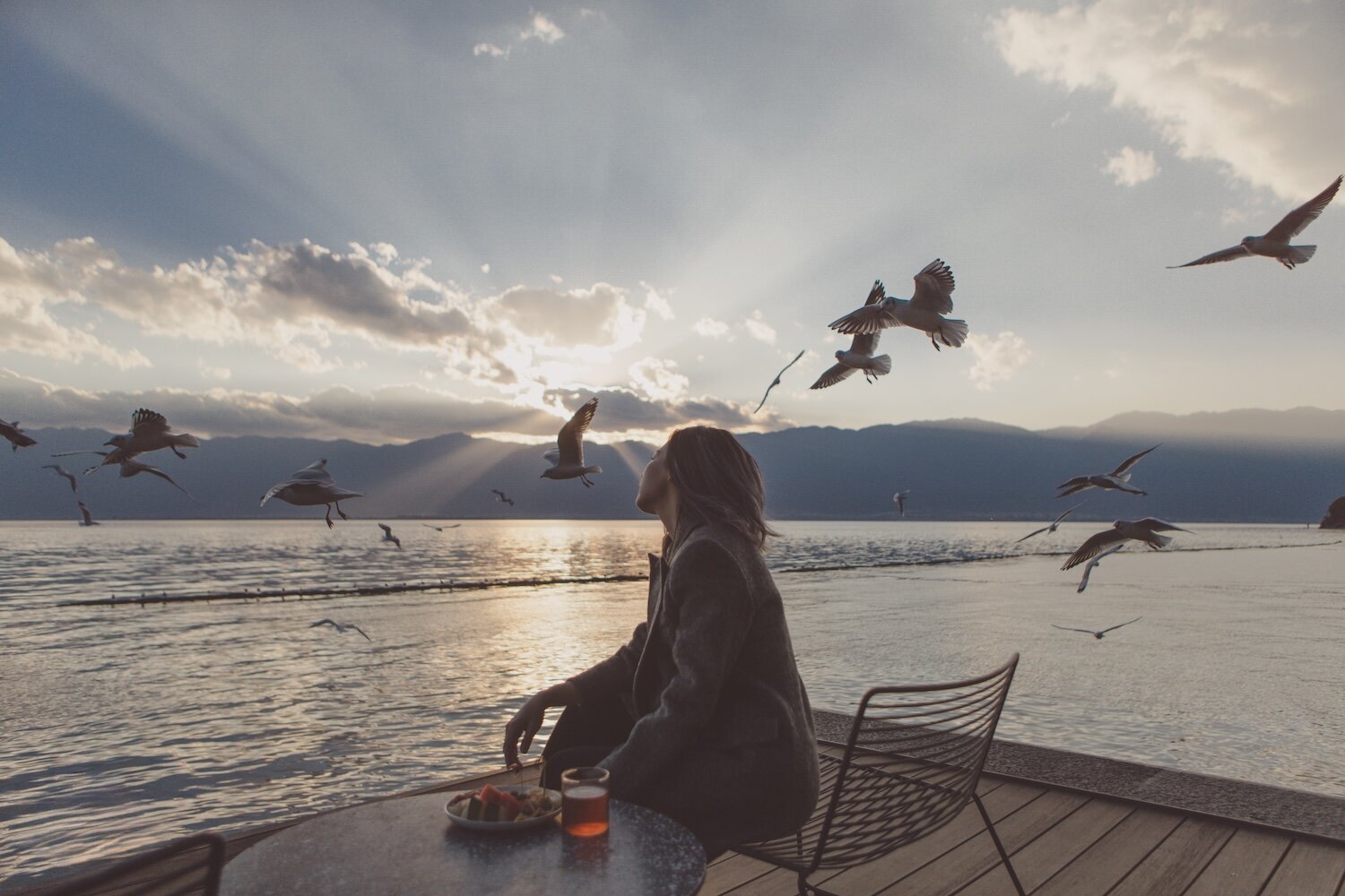 Tracy of 3N7LOVE photographed on a wharf at sunset with bird flying in the background.