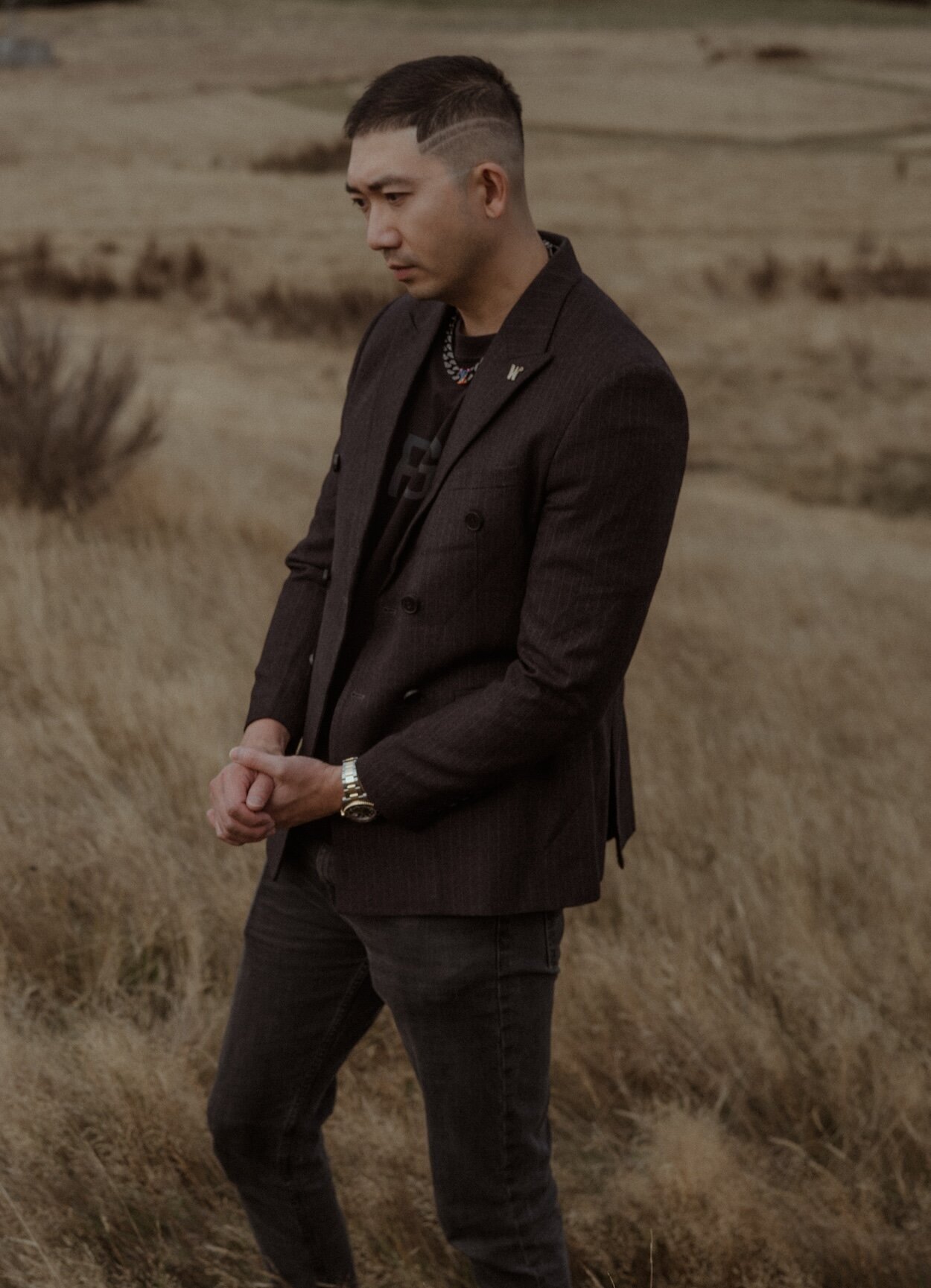 Prescott of 3N7LOVE photographed in a brown suit standing out on location.