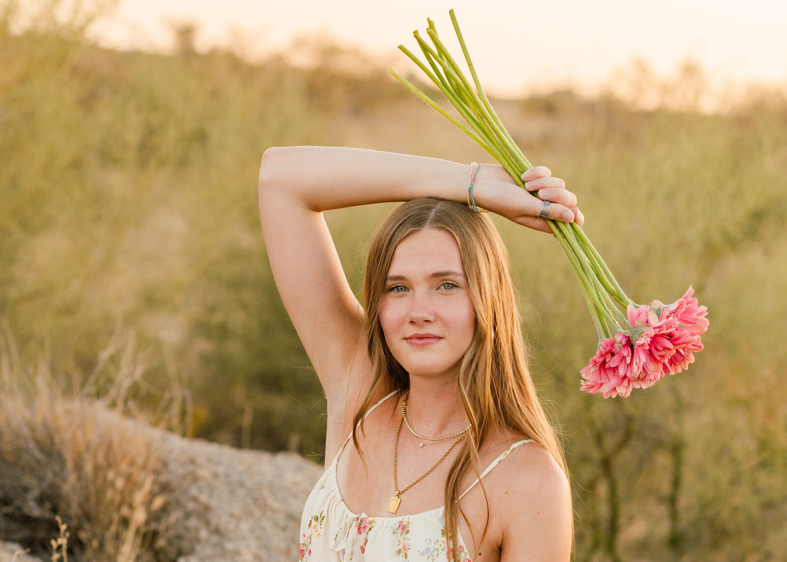 university of arizona senior in the cave creek desert holding flowers posing for senior photos