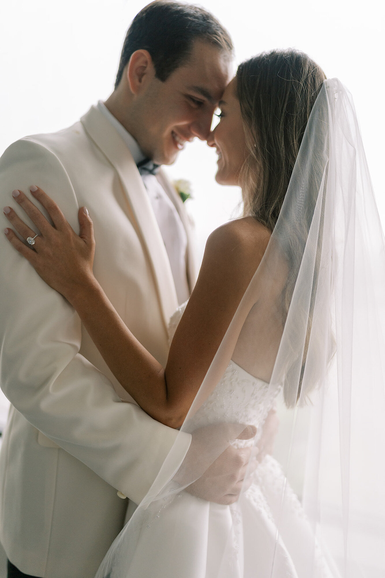 bride and groom kissing in front of window