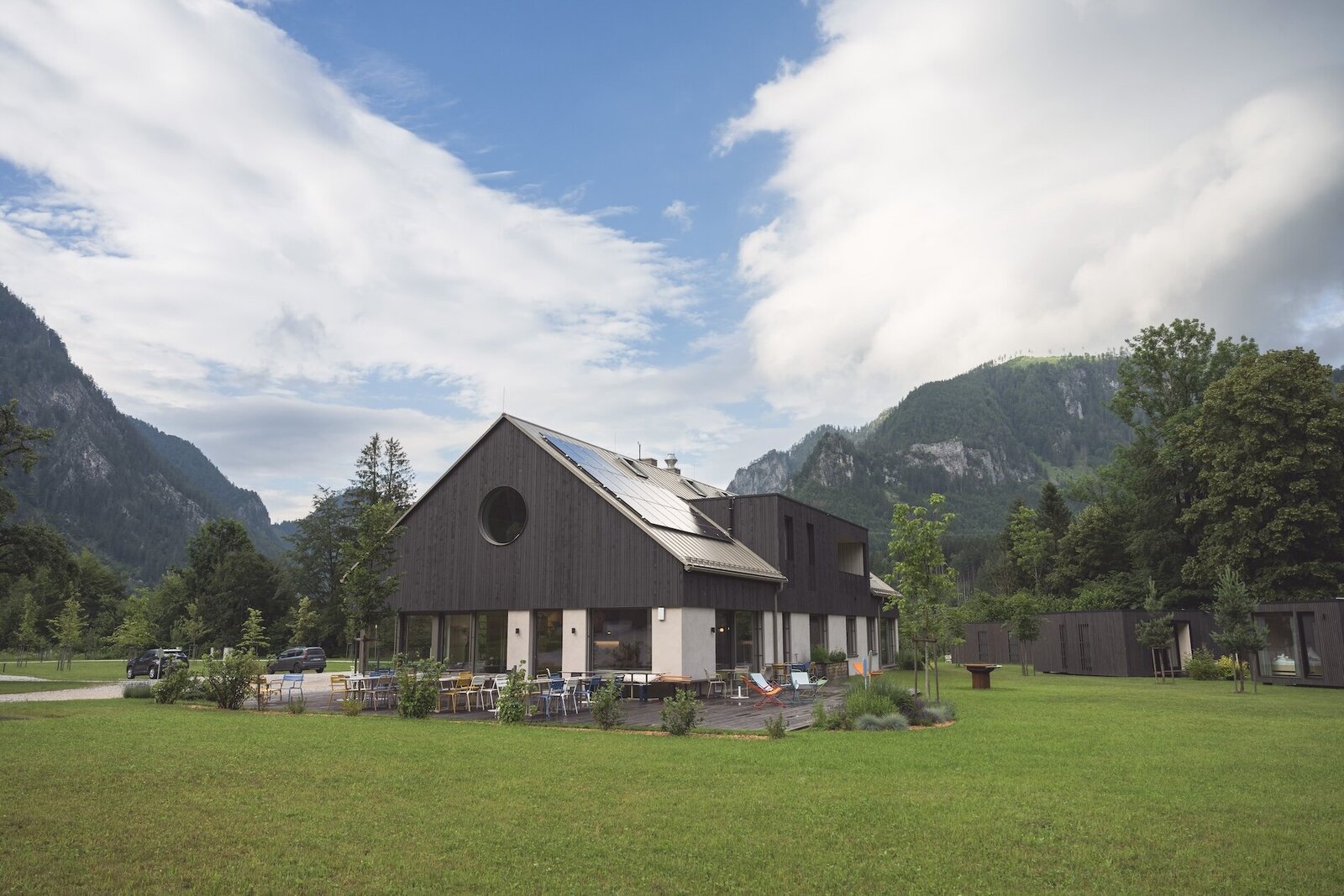 View of of The Campus Alps Workbase, framed by lush trees and majestic mountains, providing an inspiring setting for remote work, company retreats, and outdoor activities in the heart of the Alps.