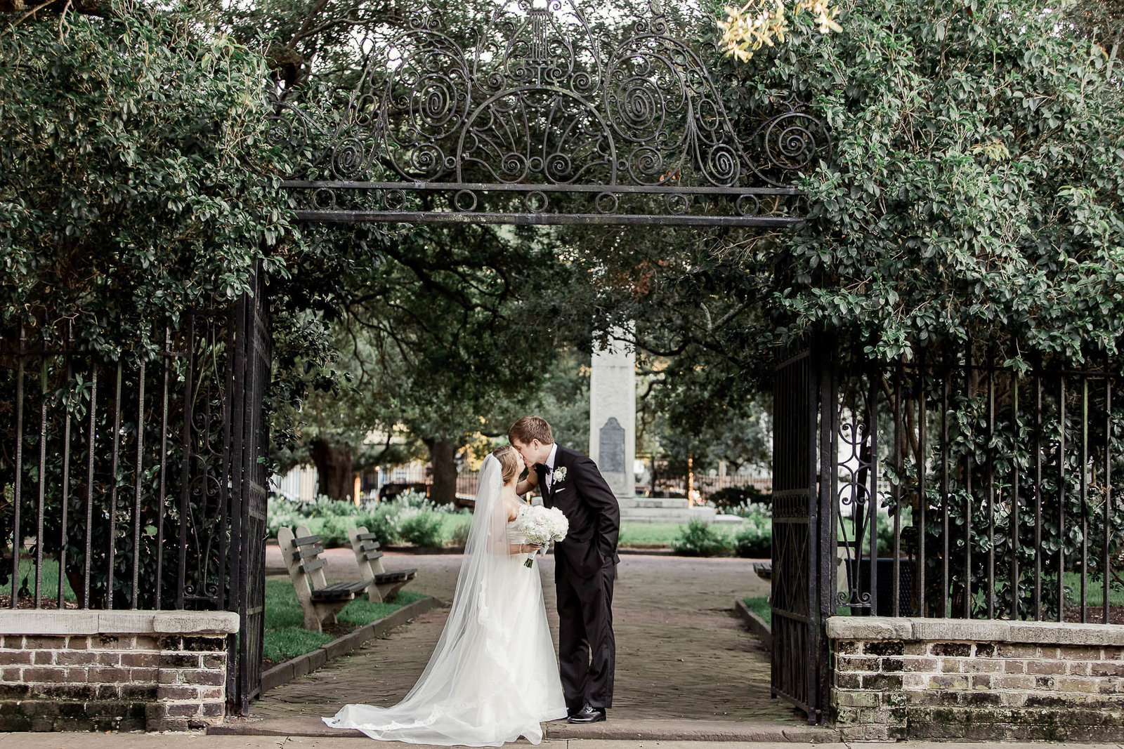Bride and groom stand at the wrought iron gate of Washington Square, Charleston, South Carolina