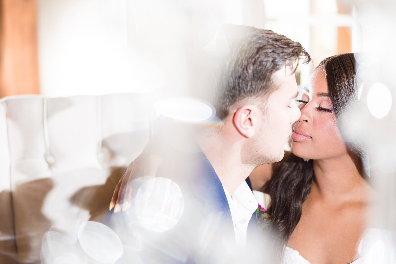 Wedding couple kiss at sweetheart table at the English Barn Wedding Venue