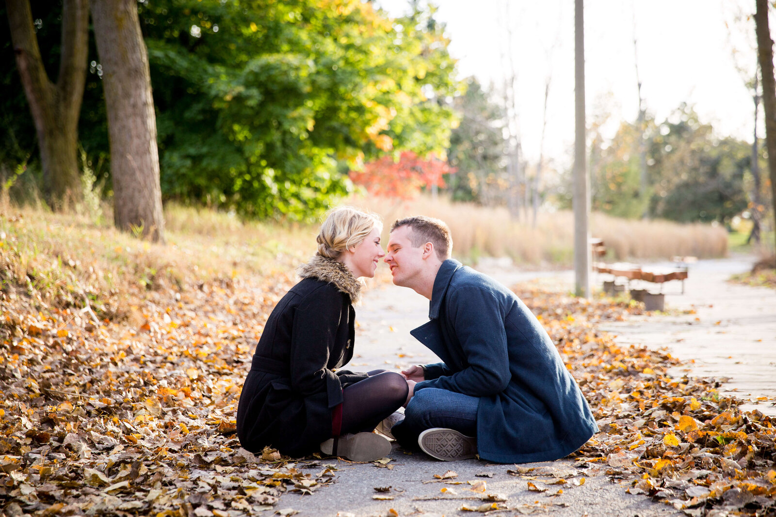 Couple sit in leaves and kiss at Toronto beach.