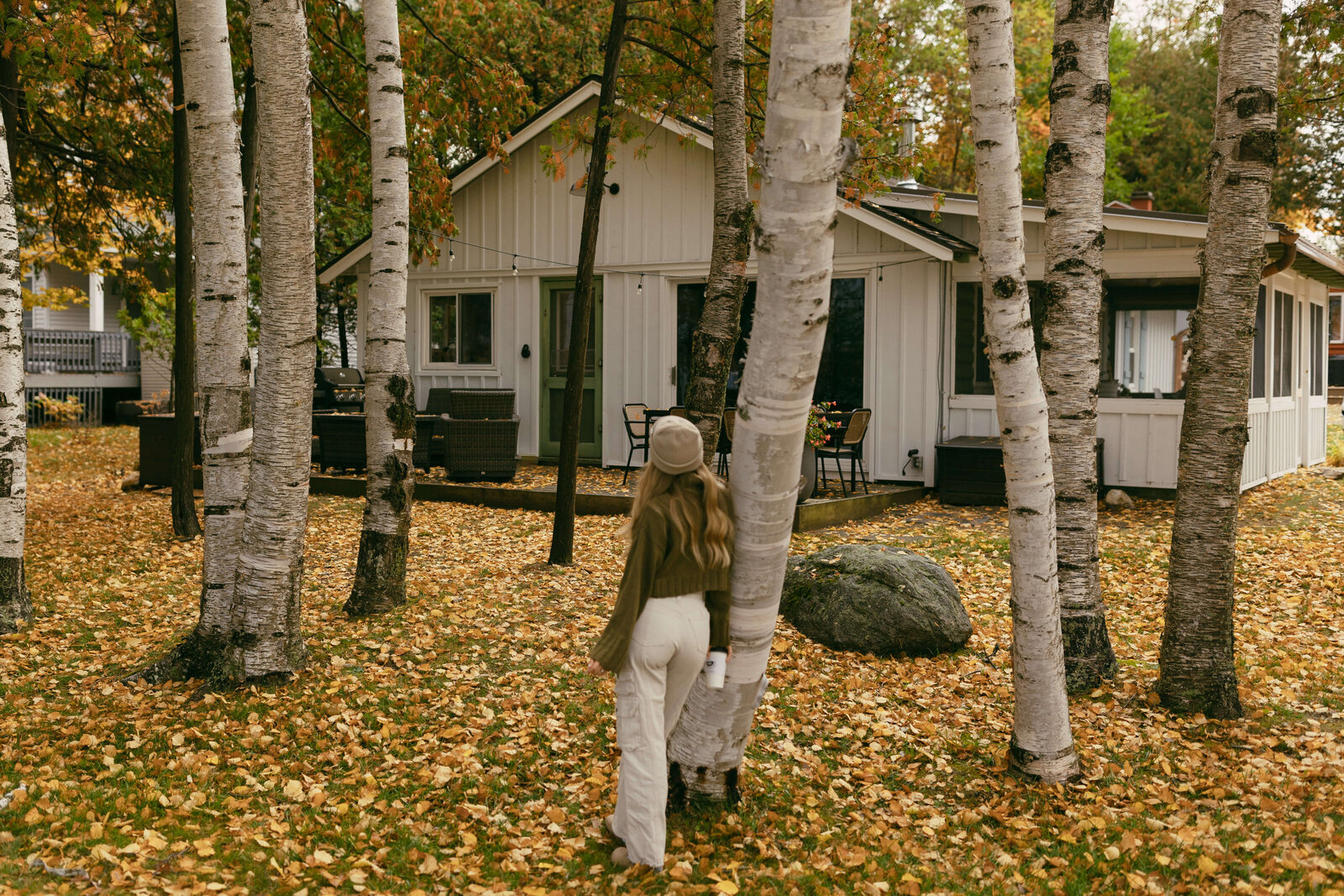 Woman standing against tree during fall outside cottage