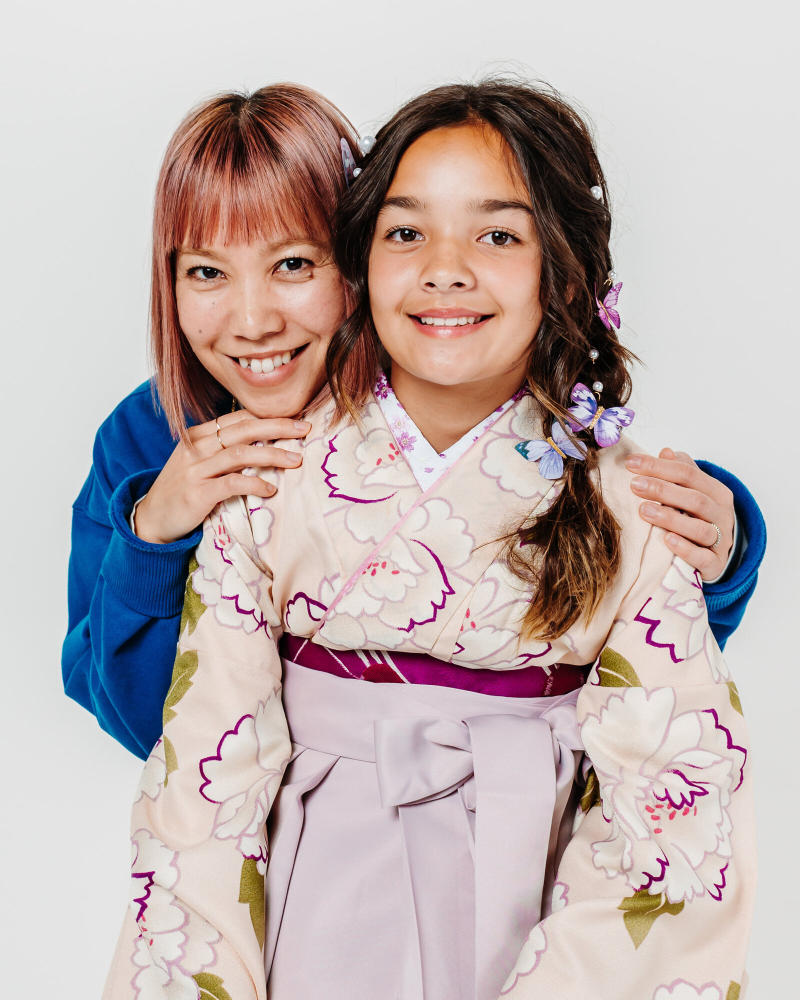 Girl in a pale pink hakama smiling with her mother, both facing the camera | 卒業式 薄桃色の袴姿で母親と笑顔を見せる女の子