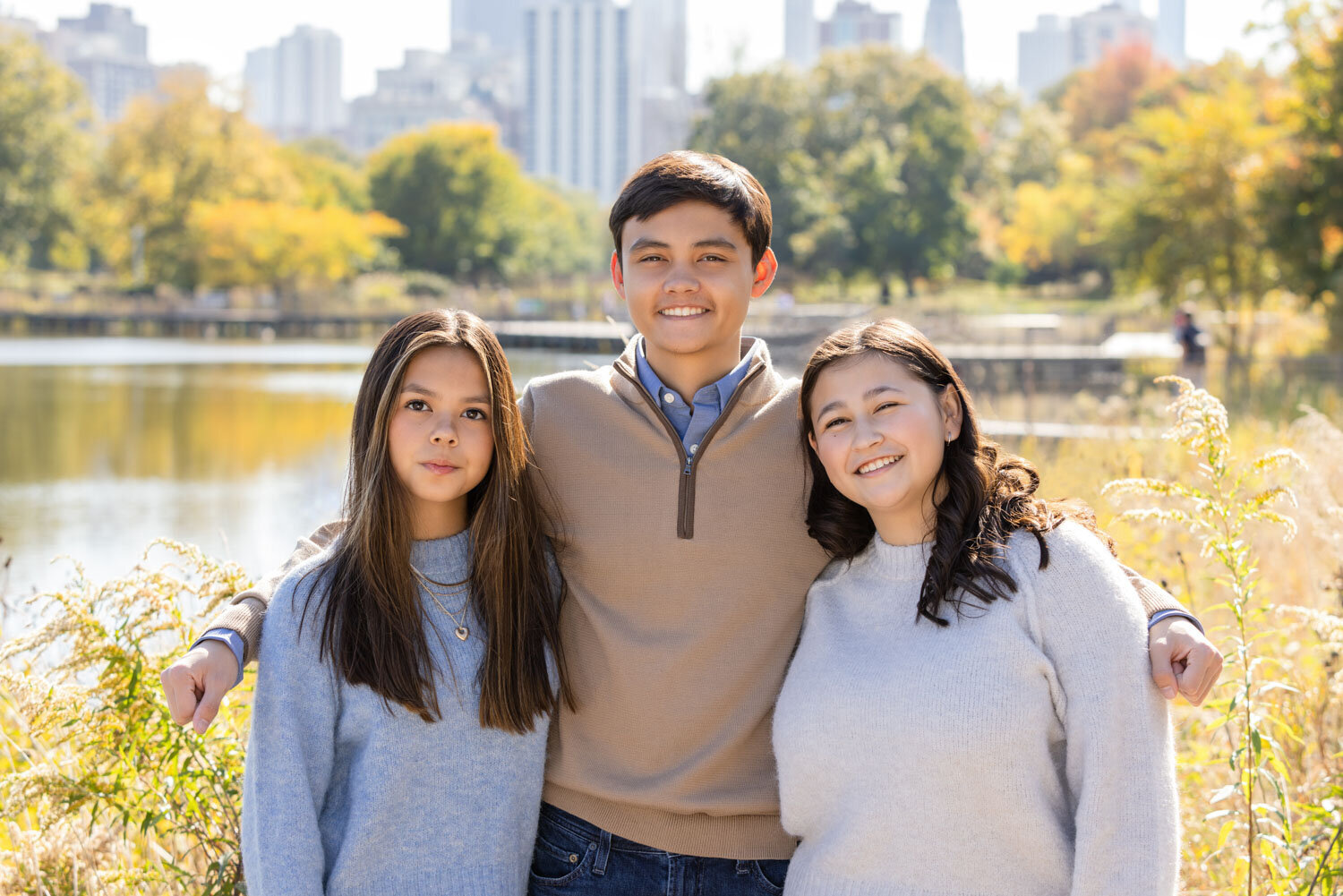 A boy and two girls pose for a picture in a park