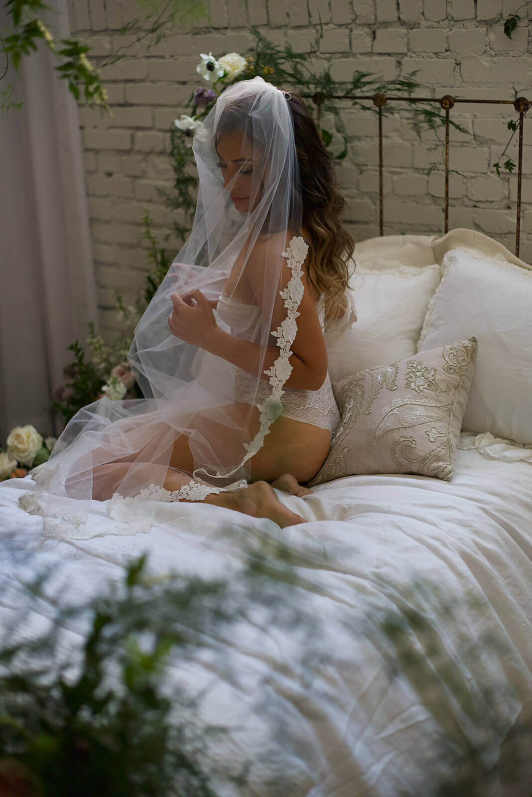 Woman in white lace lingerie on bed with wedding veil over her head