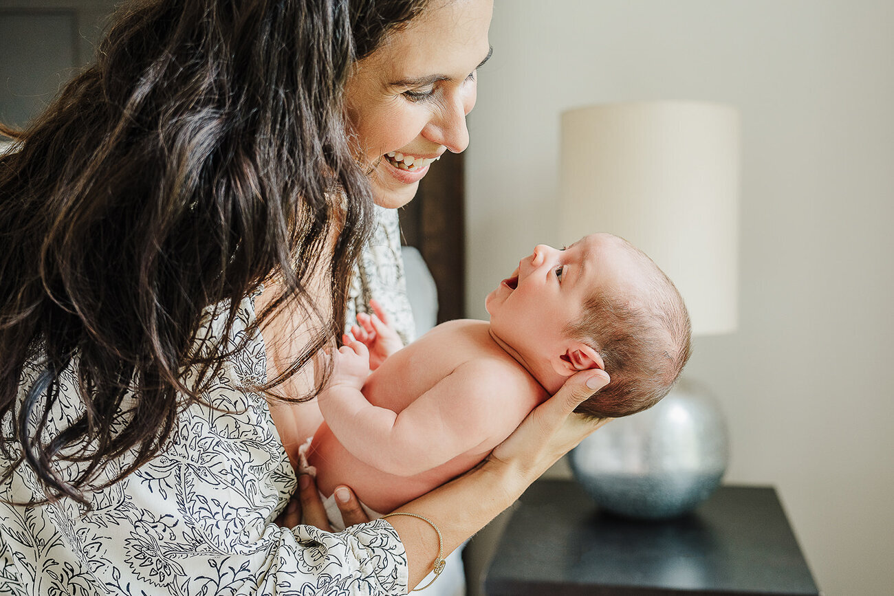 new baby smiles up at mom during boston newborn photoshoot