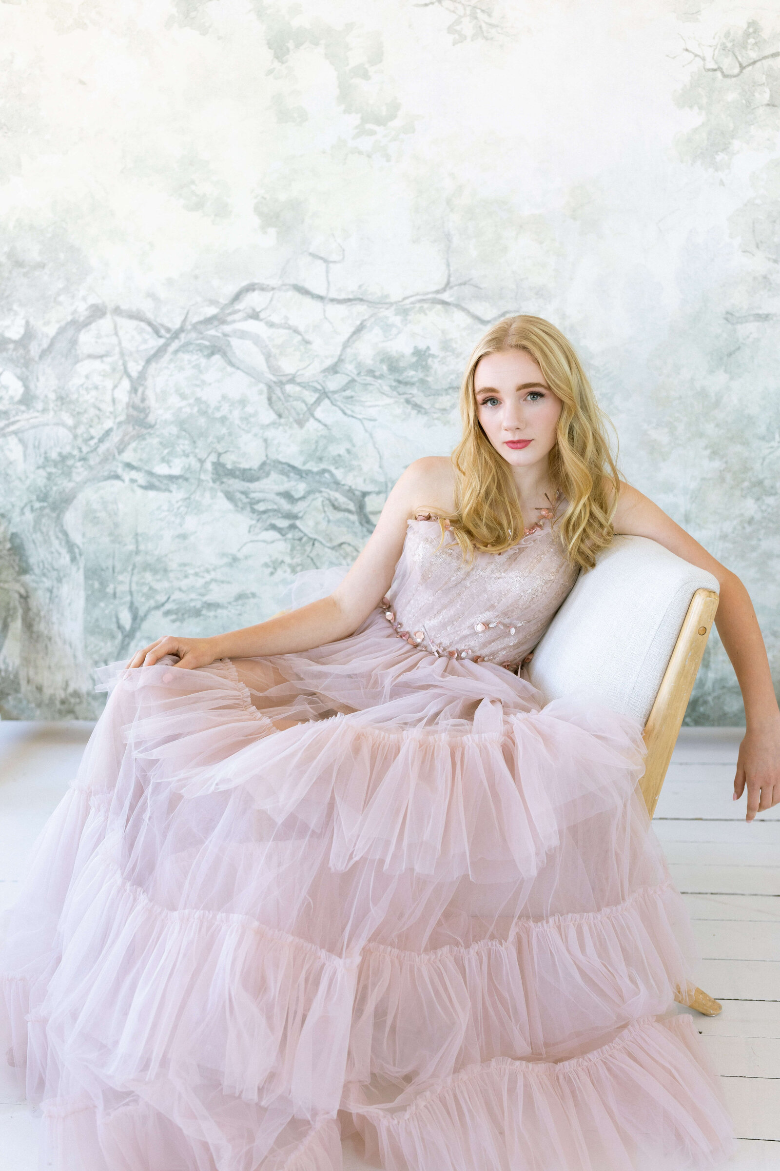 blonde girl wearing pink whimsical flowy dress and posing for senior pictures