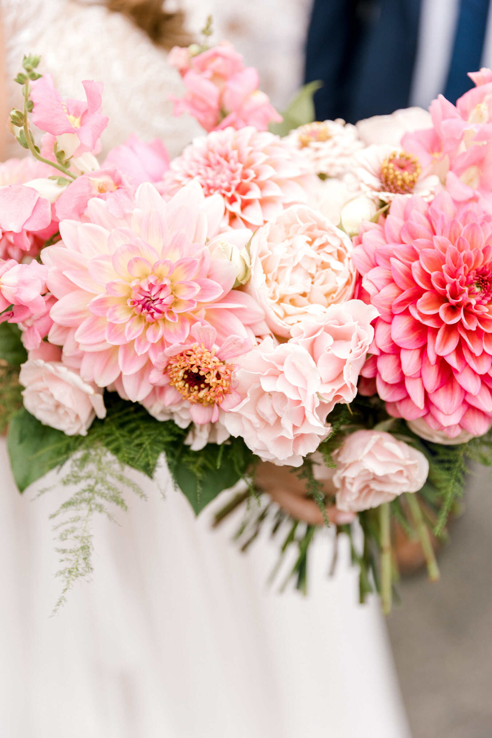 A bridal bouquet with all shades of pink roses, dahlias, spray roses and zinnias.