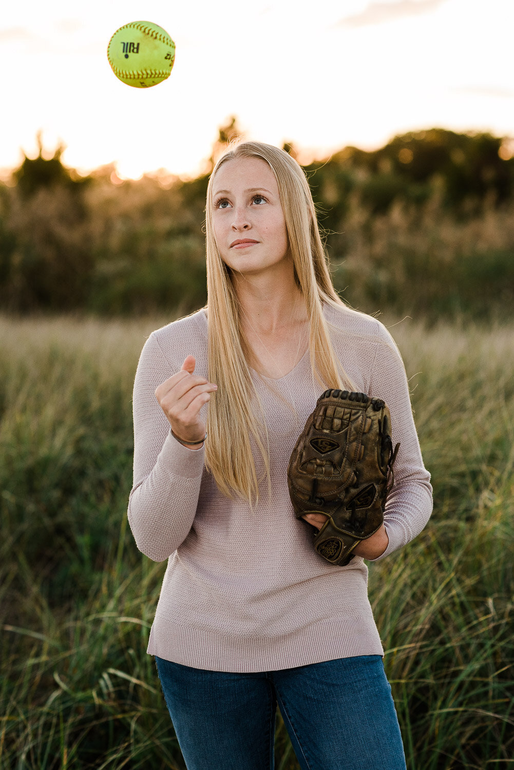 senior girl with softball glove tossing ball