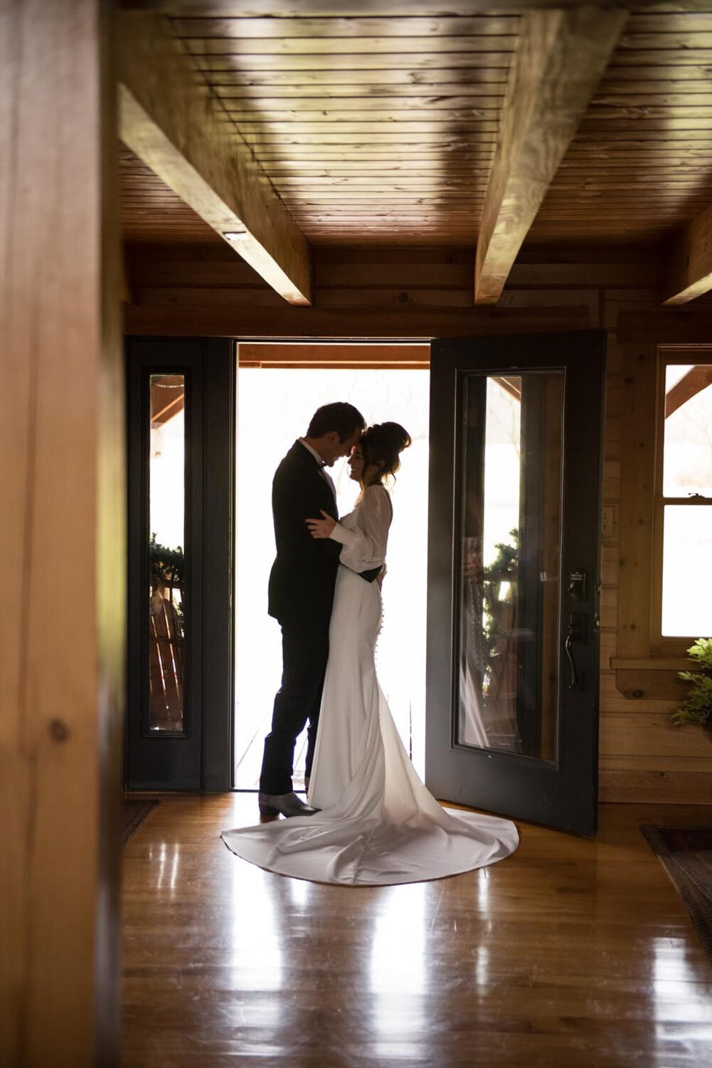 Bride and groom sharing an intimate moment inside a wooden cabin doorway