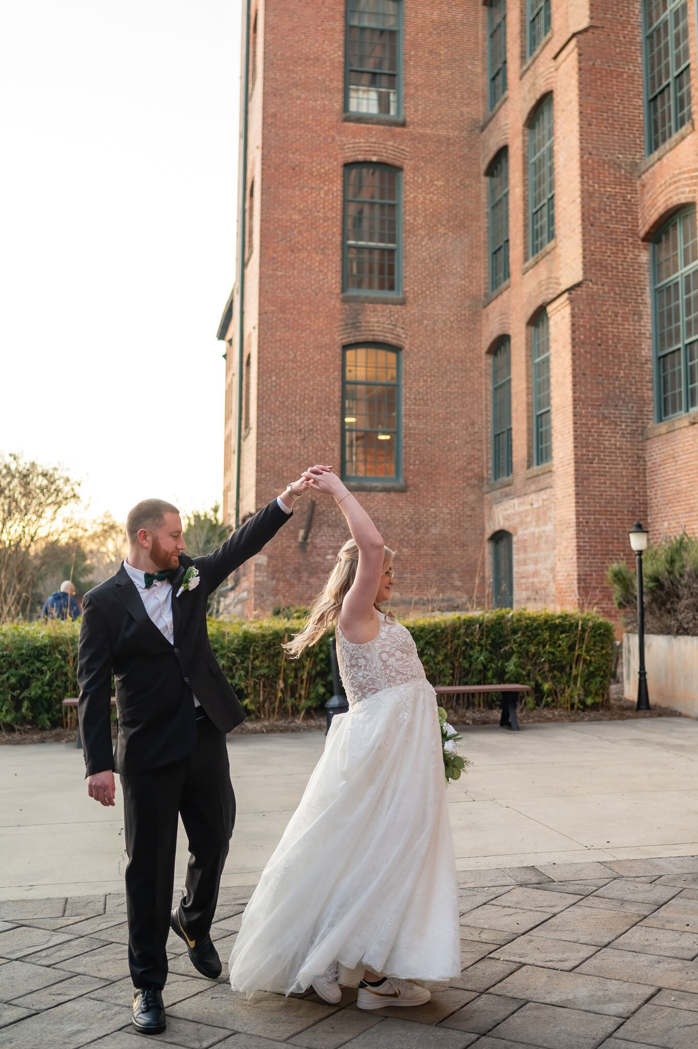 Groom twirling bride outside a historic brick building