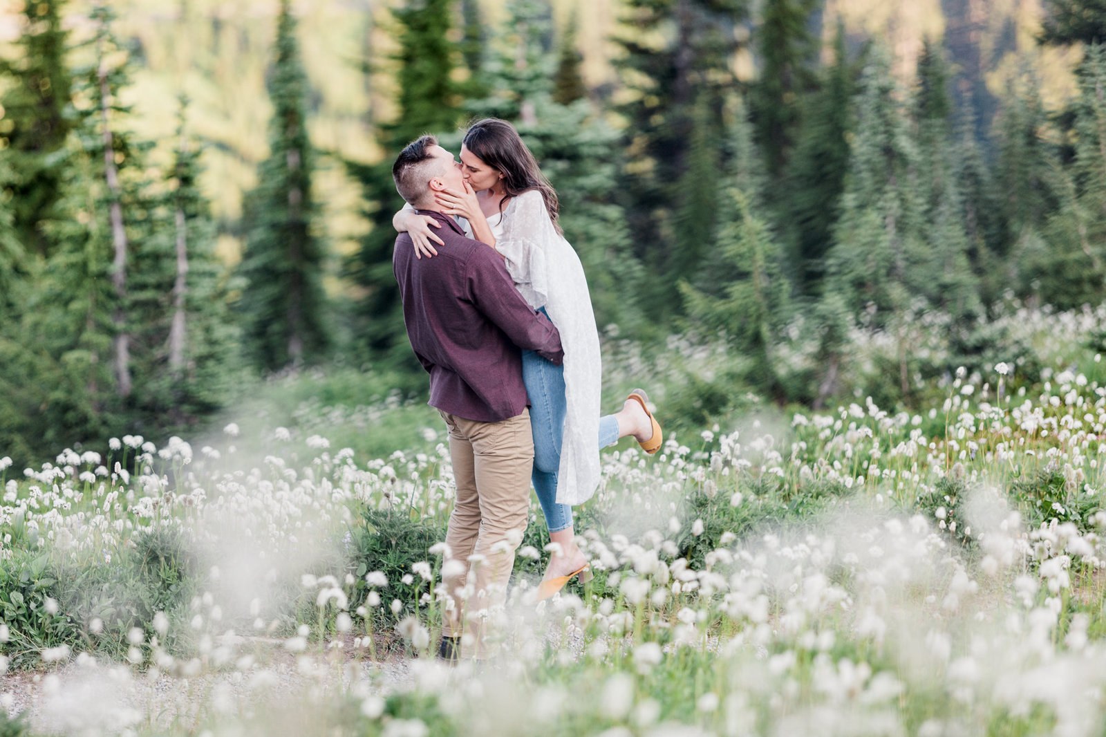 a woman is swept off her feet in a field of wildflowers at Mt Rainier National Park during an engagement photo session with mountain elopement photographer amy galbraith