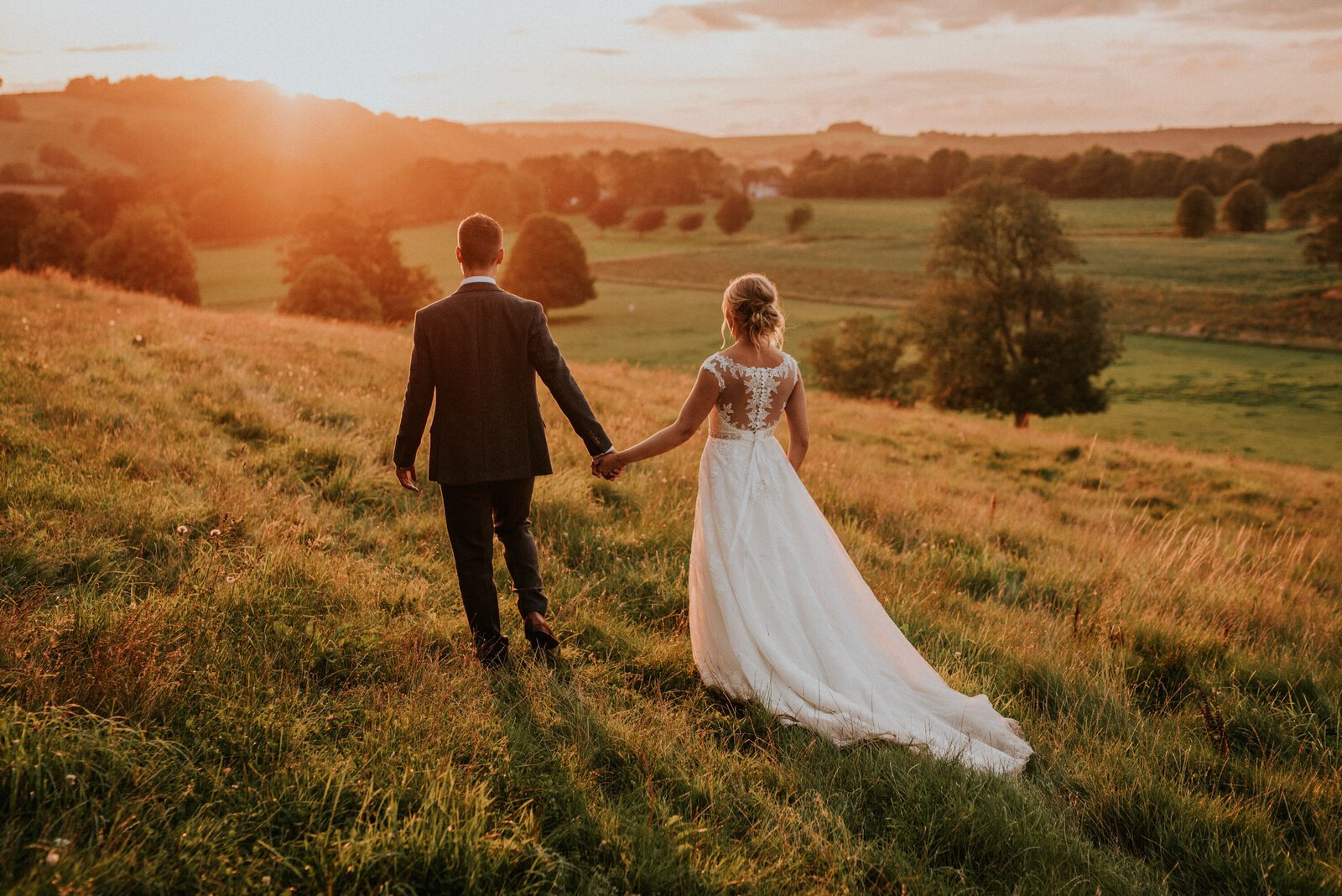 Bride and Groom walking holding hands into sunset