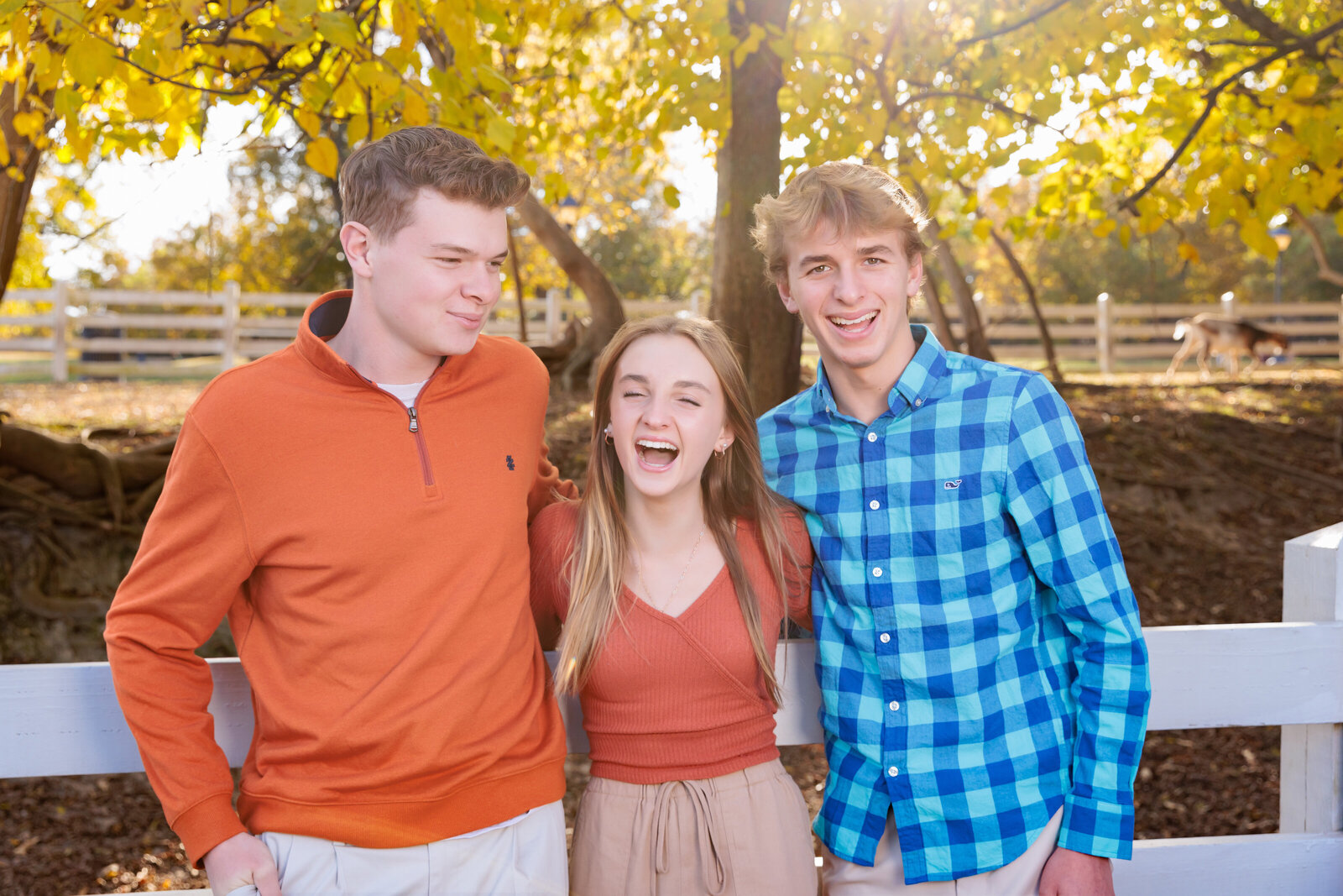 Siblings laughing in their fall portraits at Oak View in Raleigh.