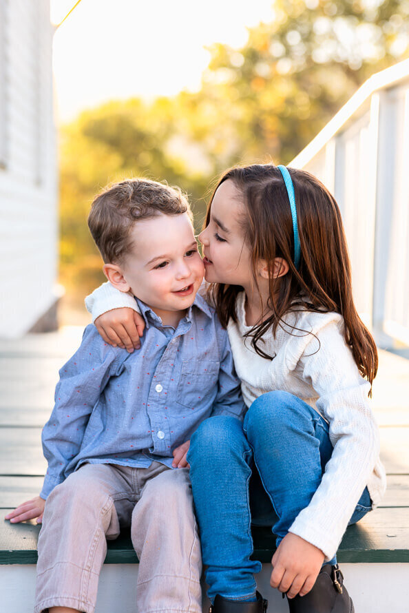 Girl gives her little brother a kiss for their family photoshoot in Golden, Colorado.
