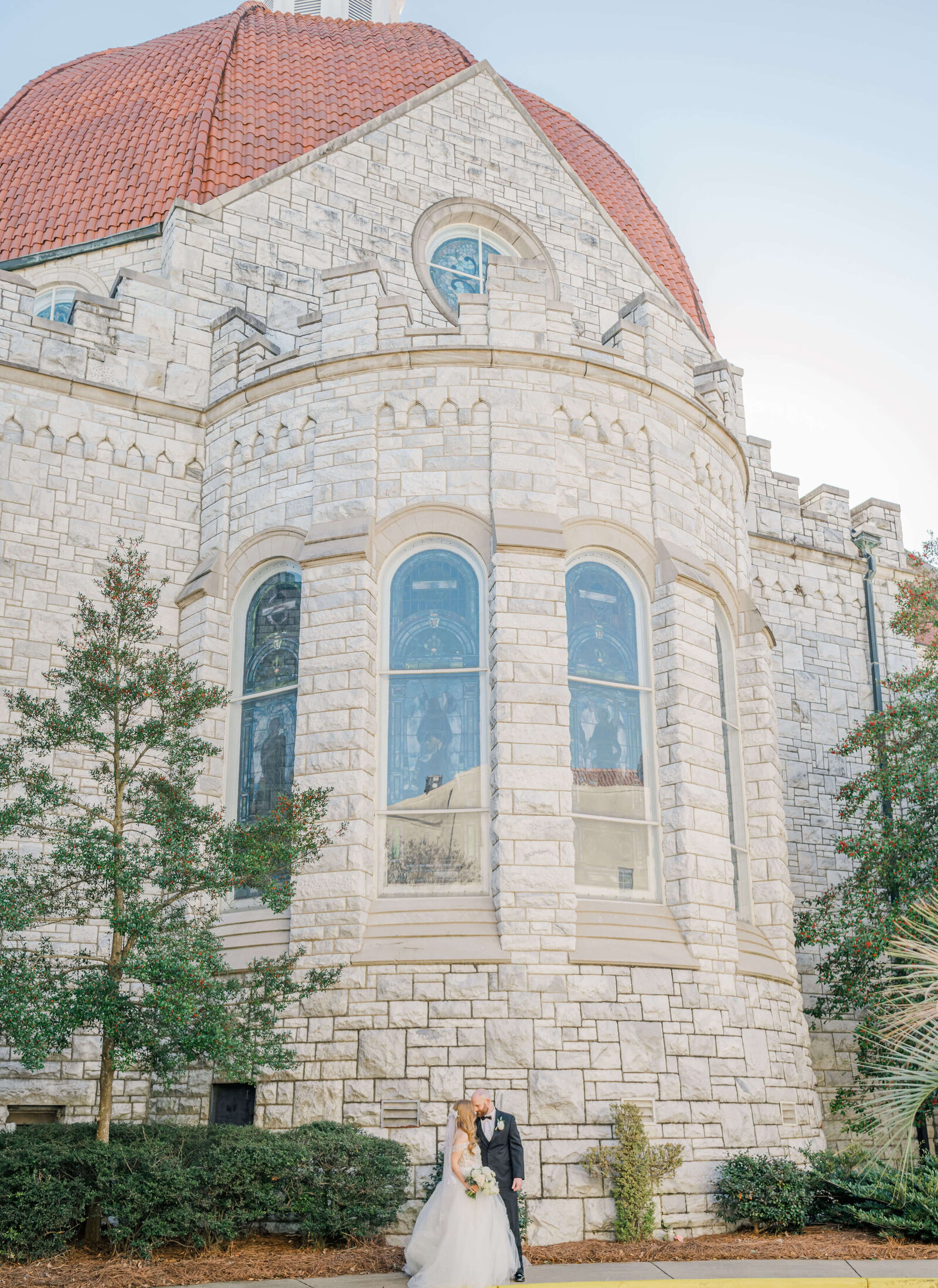 Large church building with bride and groom posing out front