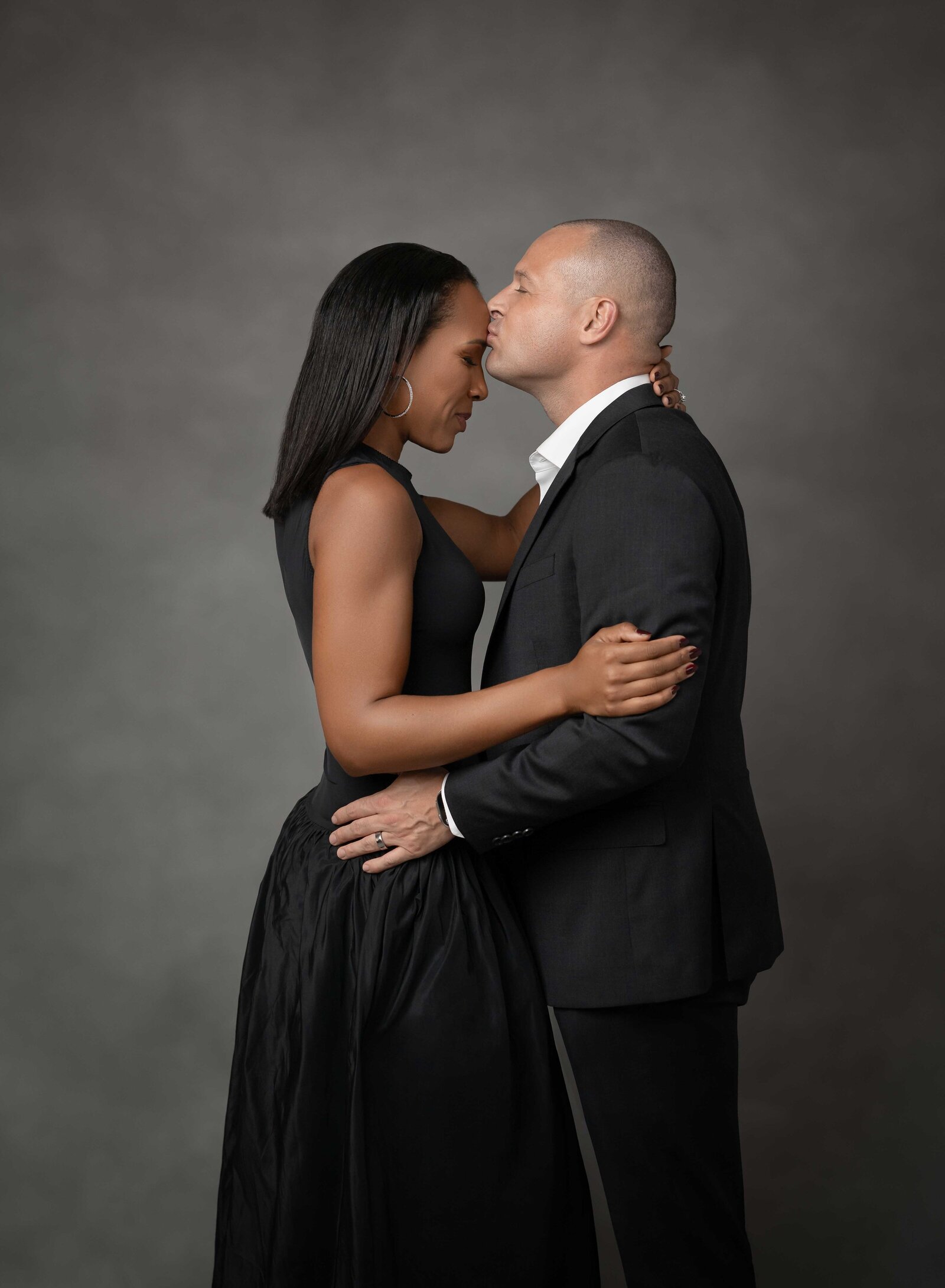 Dad kissing Mom's forehead for a professional studio photo. Family photo taken at Atlanta Photo Studio by Jenni Nikki Photography.