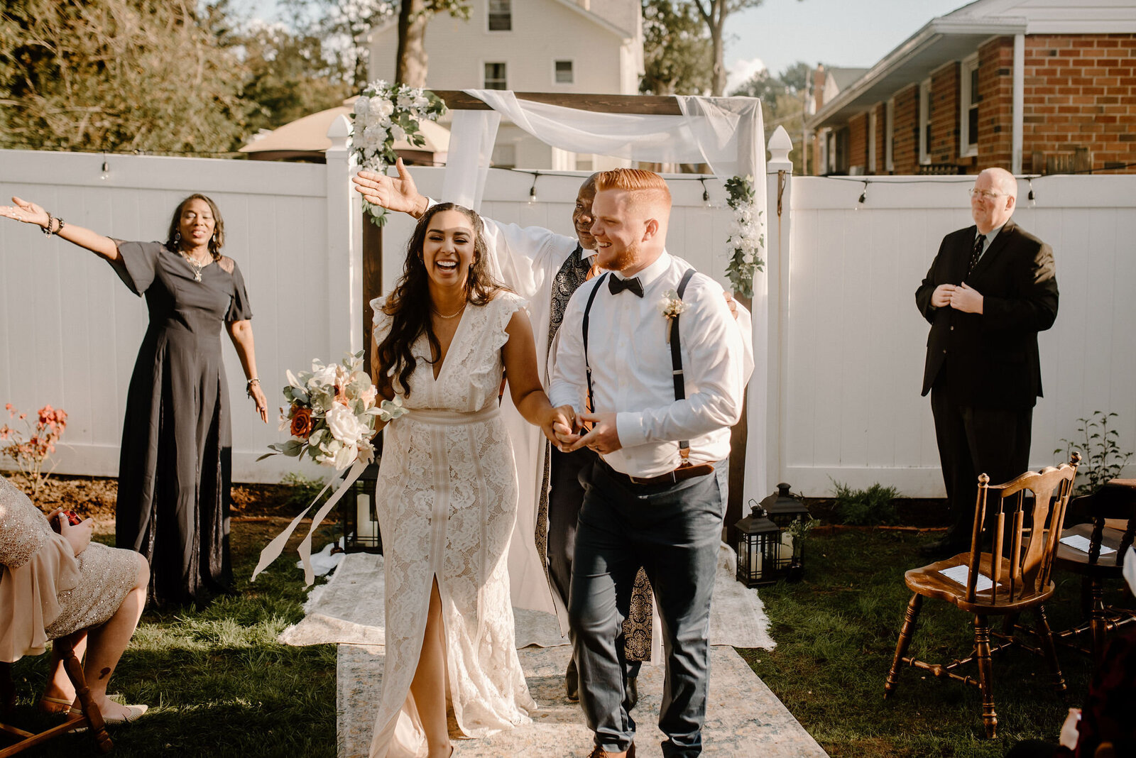 couple walking down the aisle holding hands laughing presented as husband and wife
