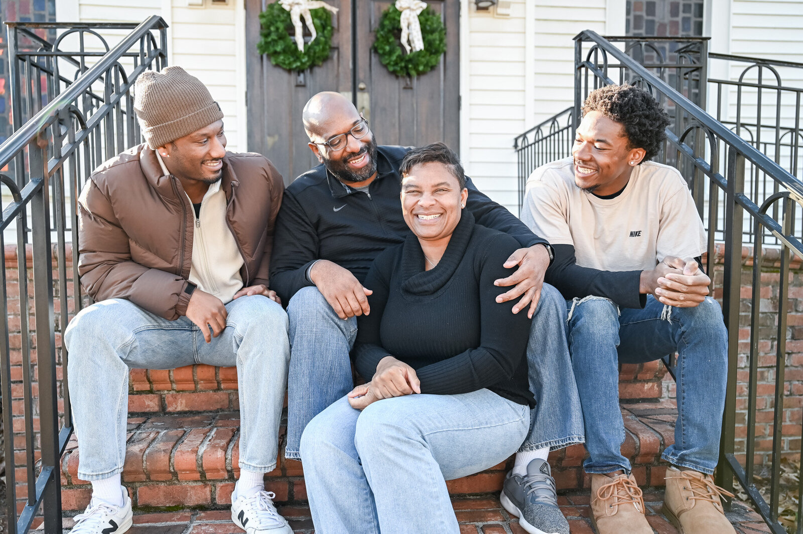 a mother and father with their two older songs sitting on the steps of their family home in Greenville, SC. photographed by Millz Photography in Greenville, SC