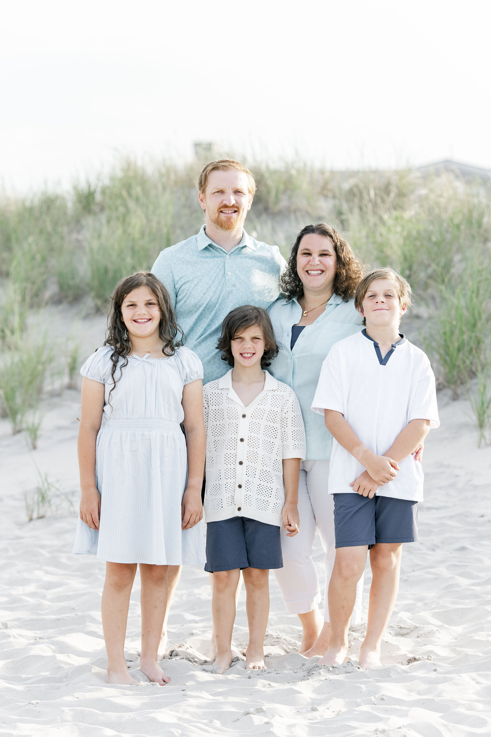 family of five standing on ocean city new jersey beach photographed by ally kimpton