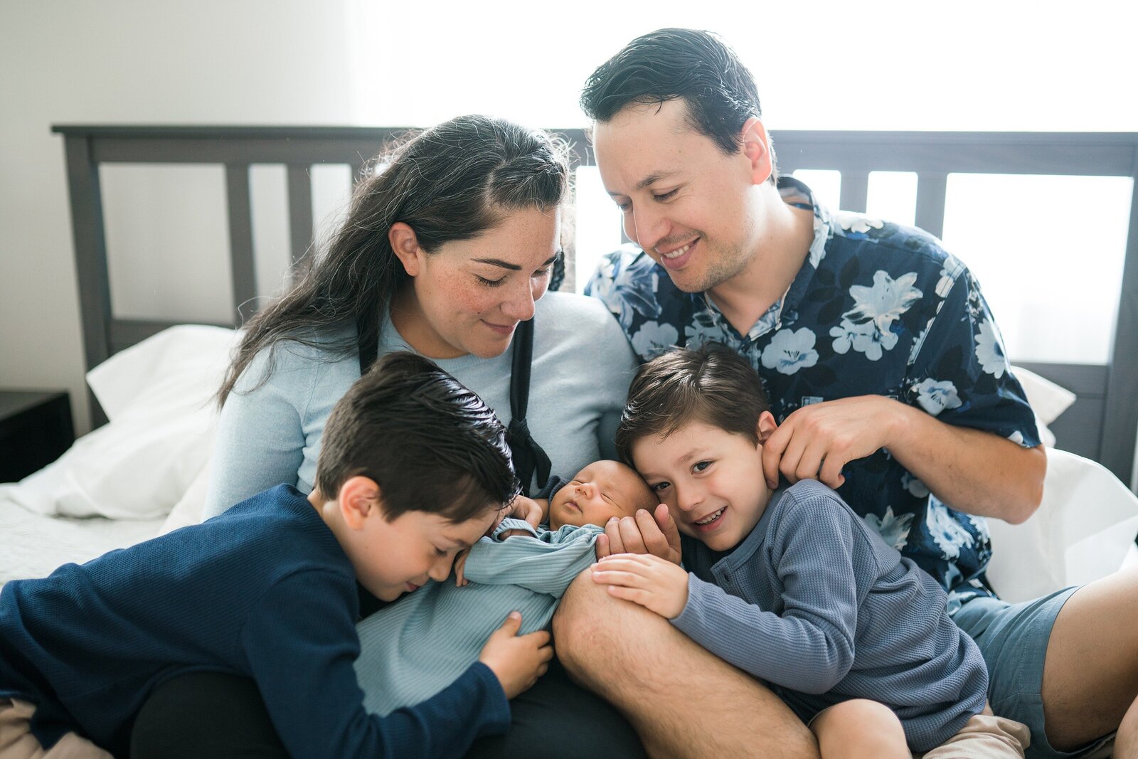 Newborn baby with older brothers and parents in blue during in home newborn photoshoot